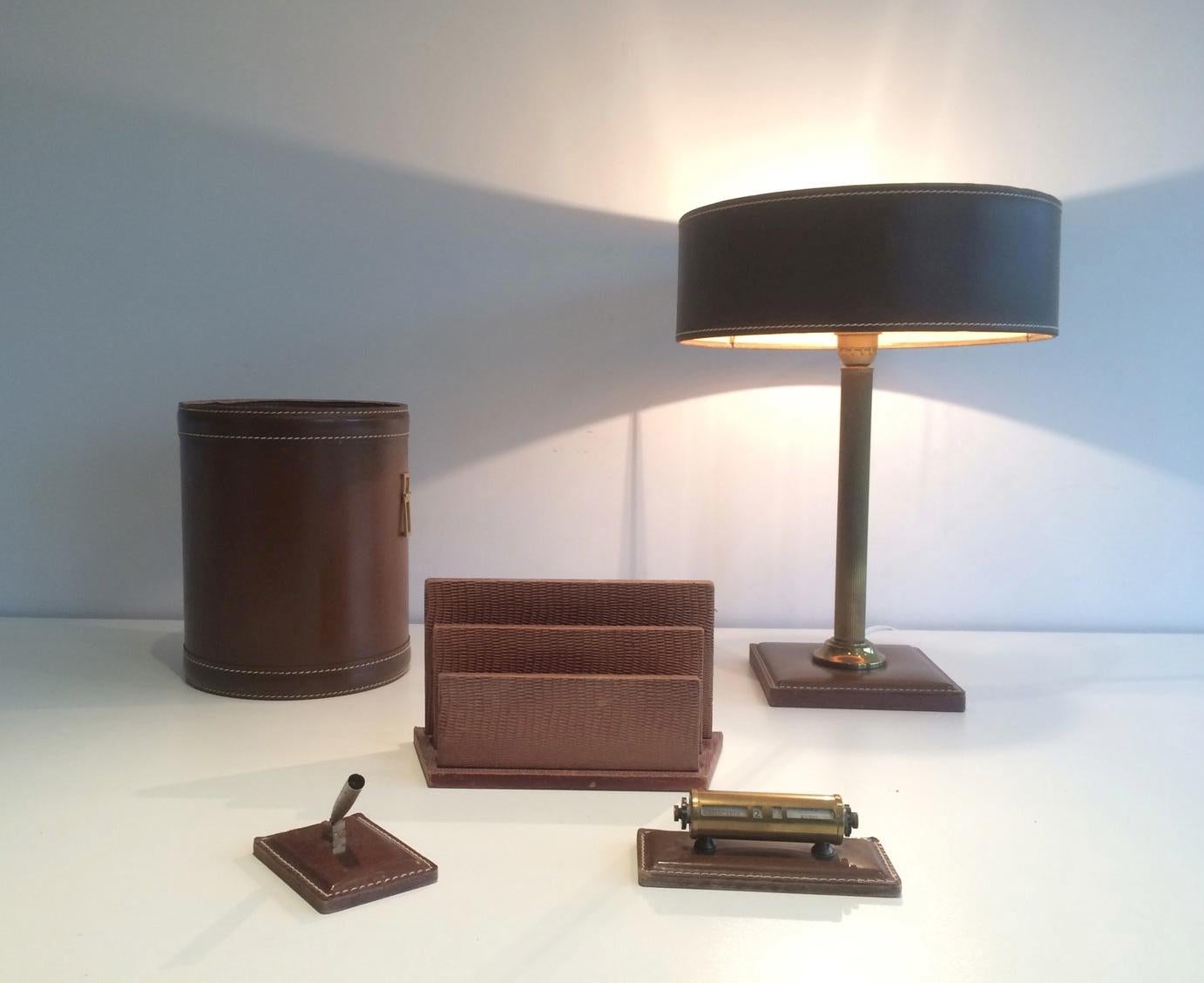 This nice desk set is constituted of a lamp, a basket, a paper holder, a diary and a pen holder. The all set is made of leather and brass. This is a French work, circa 1970.