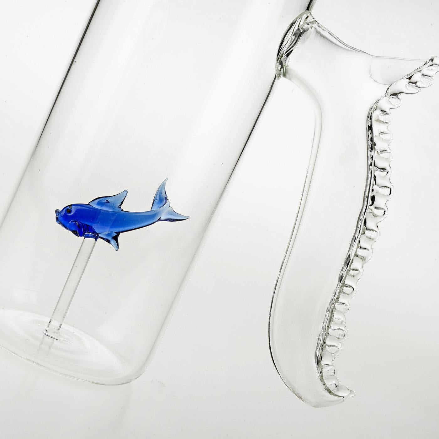 This set comes complete with one tall cylindrical pitcher with a nautical handle, and four rounded glasses slightly tapering at their tops. What makes this collection unique is the addition of a expertly crafted royal blue glass fish, seeming to