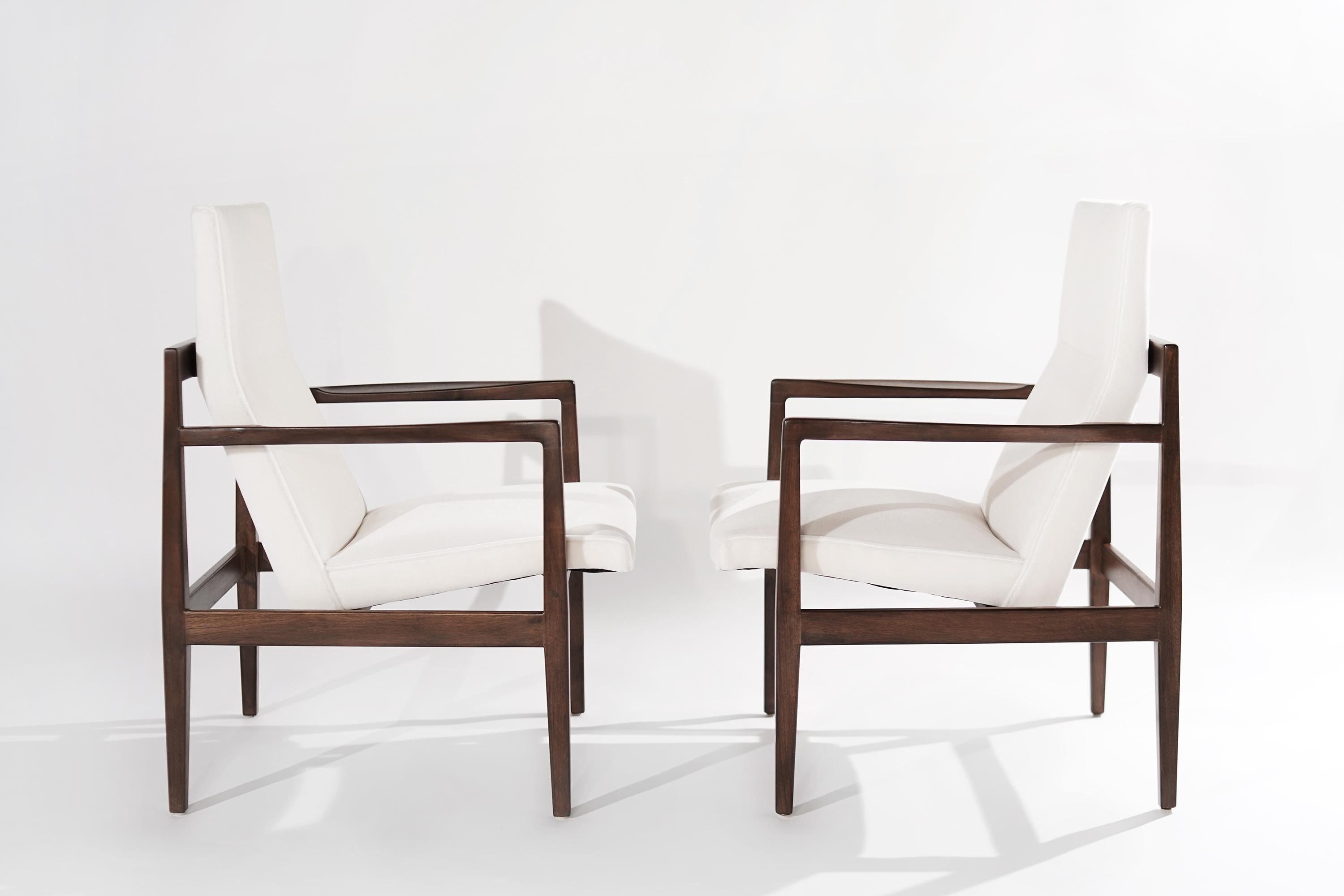 Pair of high-back lounge chairs designed by Jens Risom, featuring fully restored open-arm walnut frames, boasting clean, elegant lines from all angles. Newly upholstered in mohair by Holly Hunt. 

Other designers from this period include Finn Juhl,