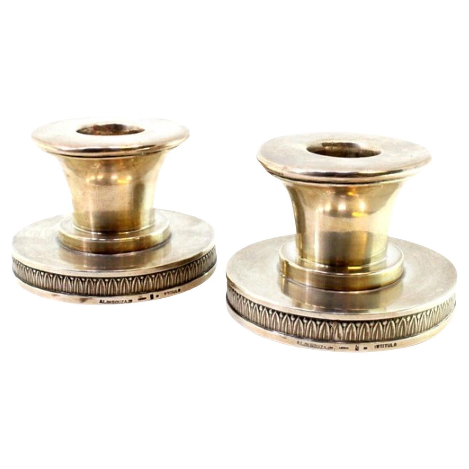 Set of low silver candlesticks set on circular bases with relief friezes