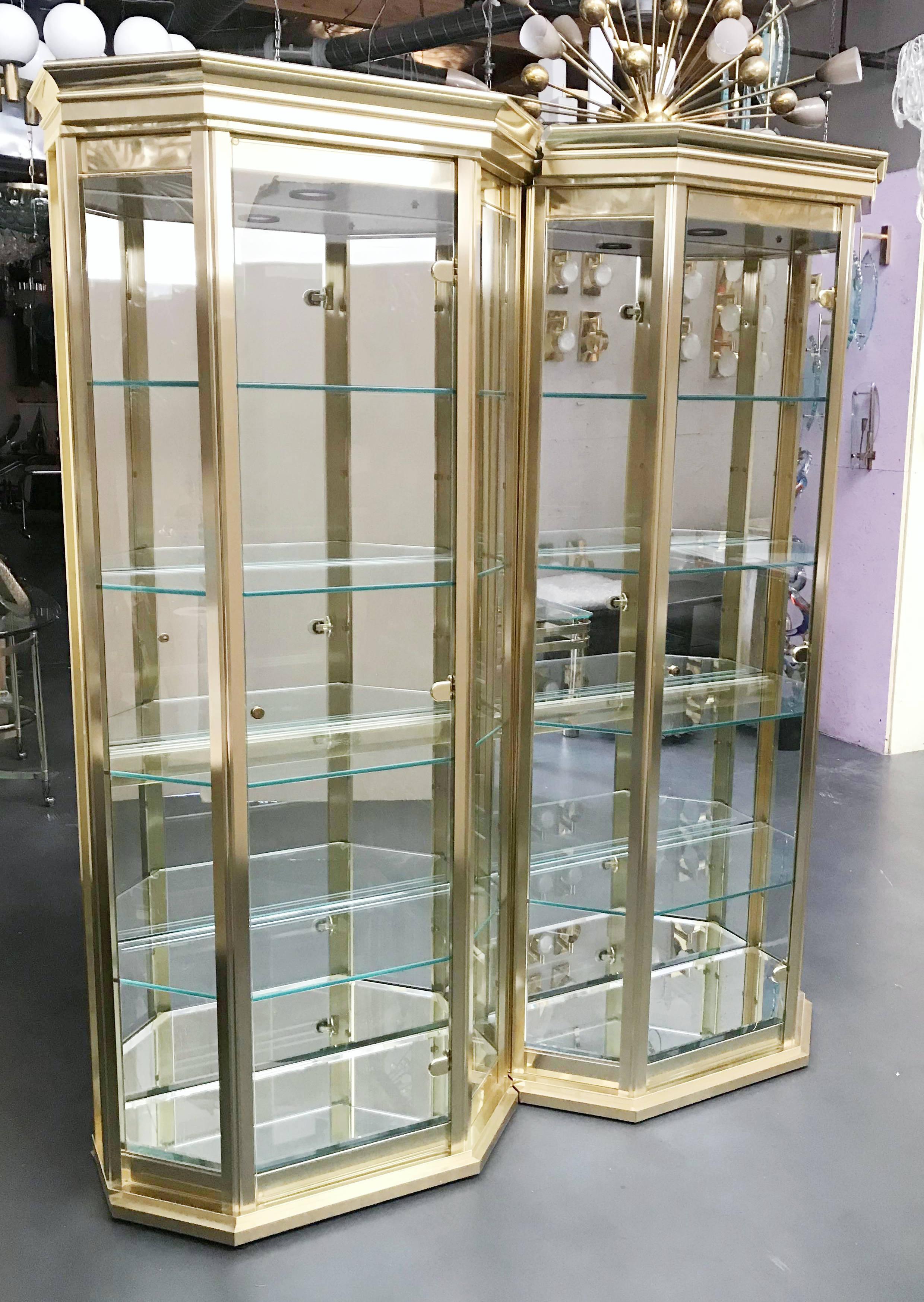 Set di vetrine o vetrinette di metà secolo splendidamente progettate e realizzate da Mastercraft, in eccellenti condizioni vintage.
Due armadi con modanature in ottone satinato, pannelli in vetro spesso, porte e ripiani. Una luce a scomparsa con