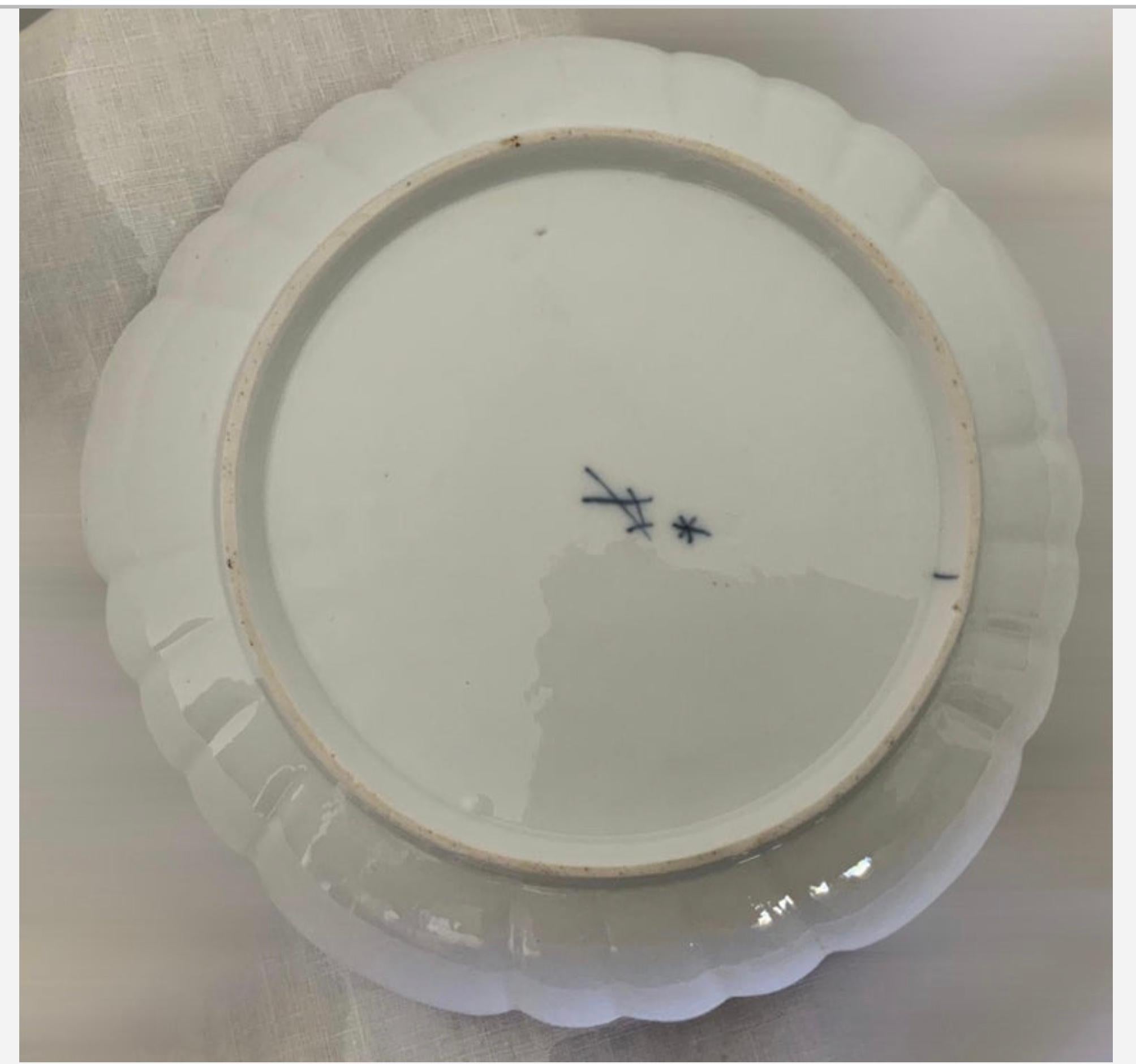 Il s'agit d'un ensemble d'assiettes et de bols en porcelaine de Meissen peints à la main. Il représente au centre un couple de chérubins tenant une guirlande de fleurs et une couronne de feuilles vertes alors qu'ils sont au paradis. L'autre plaque