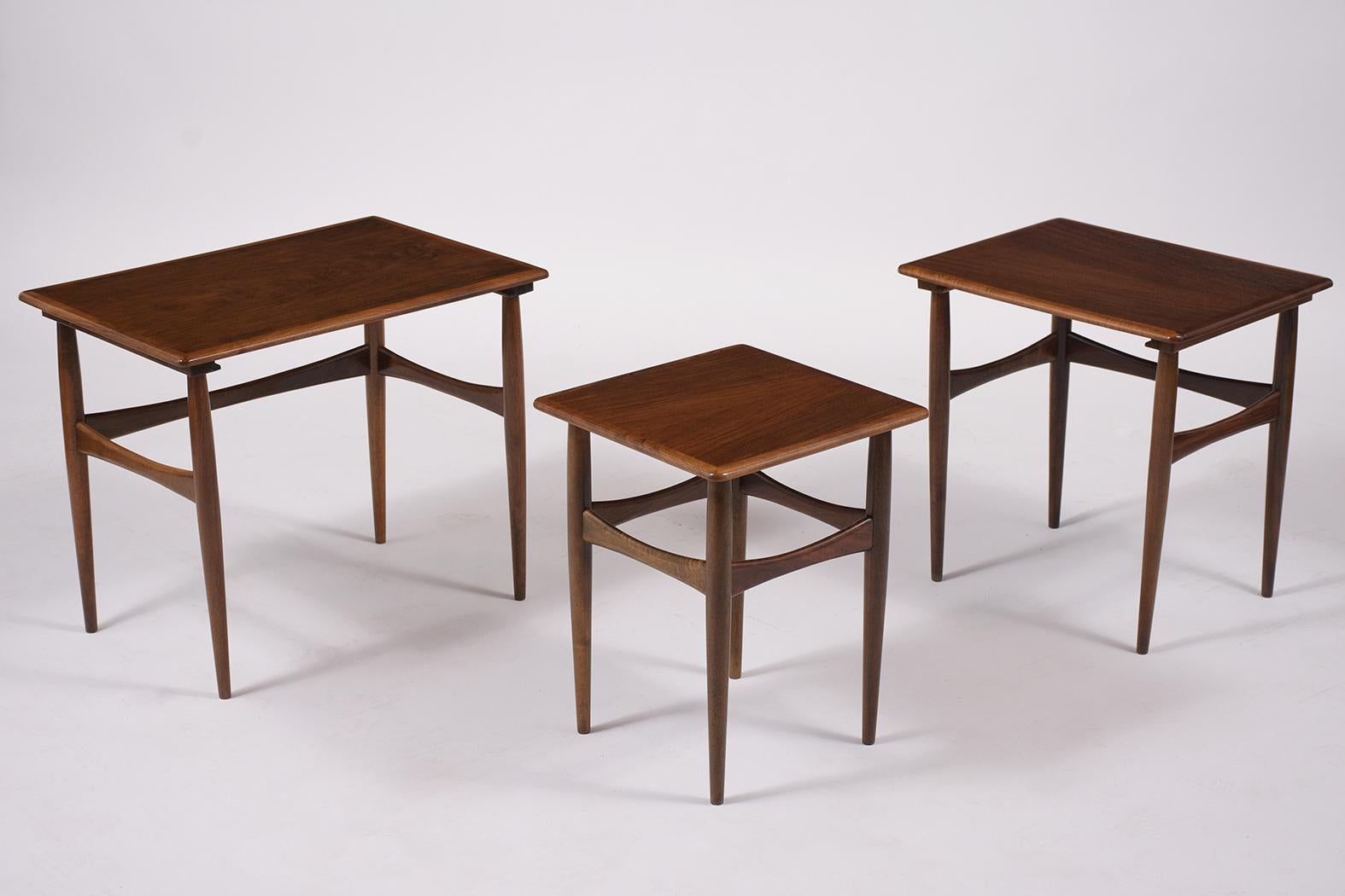 Extraordinary danish nesting tables crafted out of teak wood have been professionally restored by our team of expert craftsmen. these side tables feature framed molding tops raised by stretched tapered legs and are very sturdy stained in dark walnut