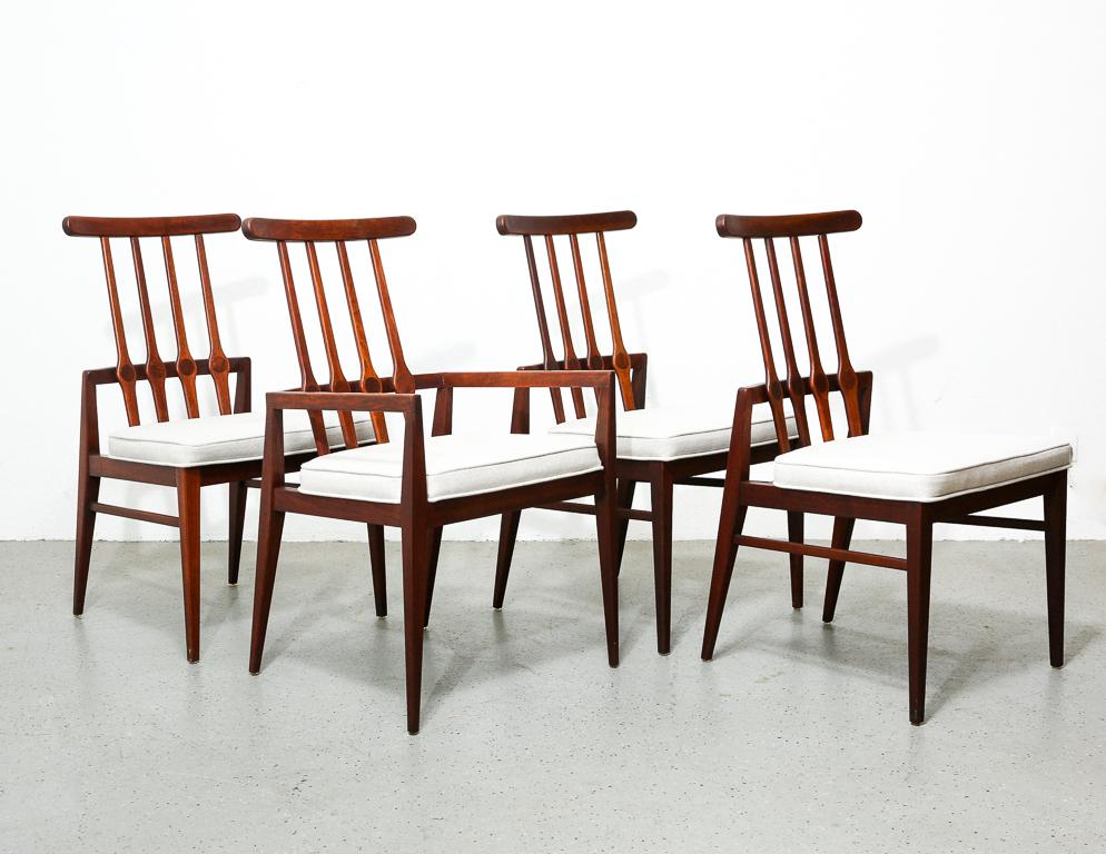 Vintage set of walnut dining chairs produced by Foster McDavid. Spindle backrests with contrasting walnut inlays and seats newly upholstered in a soft grey wool fabric. 17.5