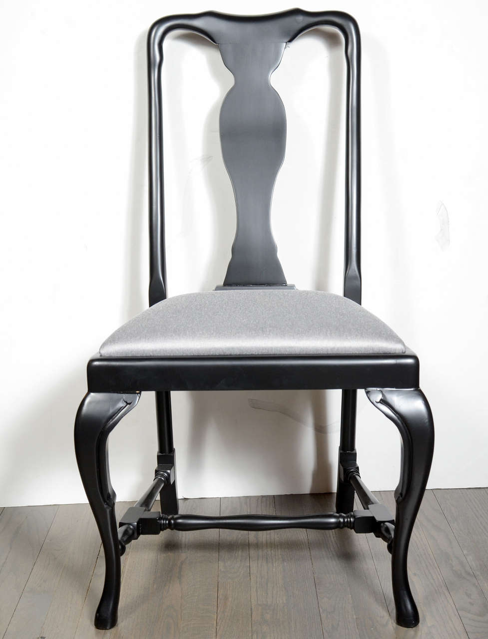 This stunning set of six Art Deco dining chairs were realized in France by the esteemed maker Jansen. They feature sculptural curvilinear ebonized walnut frames that combine clean modern lines with classical detailing; cabriole style legs and