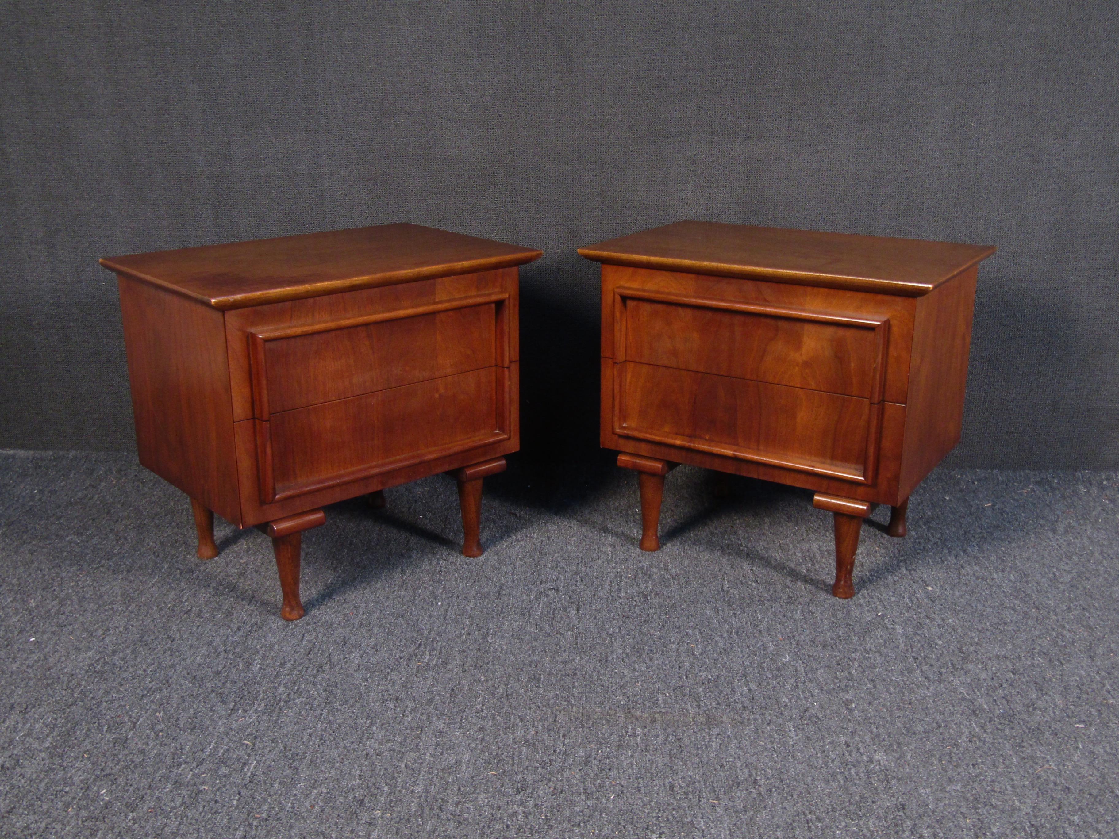 Beautiful pair of vintage modern nightstands. Well-made case pieces with a vintage walnut finish, sculpted legs, and two hefty drawers ensuring ample storage space. This sleek pair of side tables make the perfect addition to any modern interior.