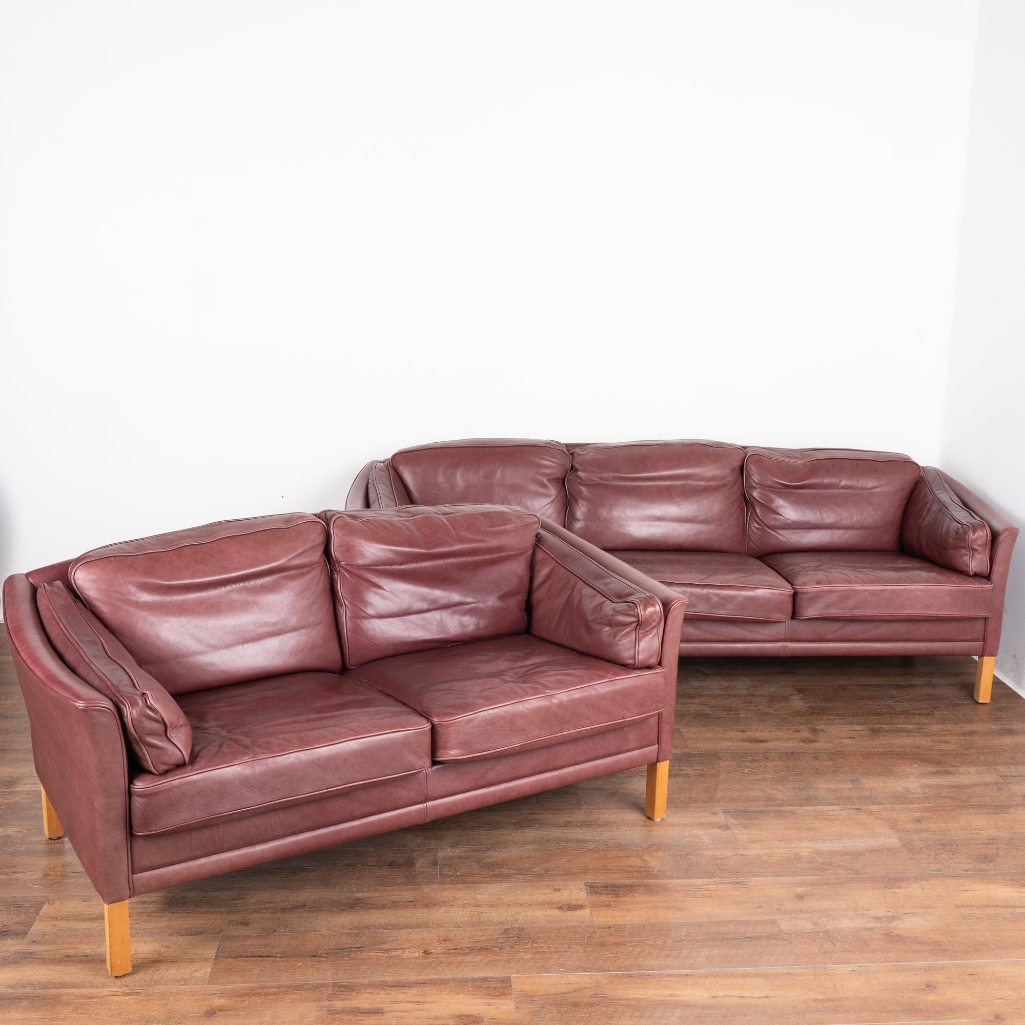 Mid-century modern three-seat sofa and two-seat loveseat set with hard wood birch legs.
Upholstered in vintage plum/light purple leather with loose cushions on the sides, seat and back. Each has a zippered cover so cushion inserts are removeable.