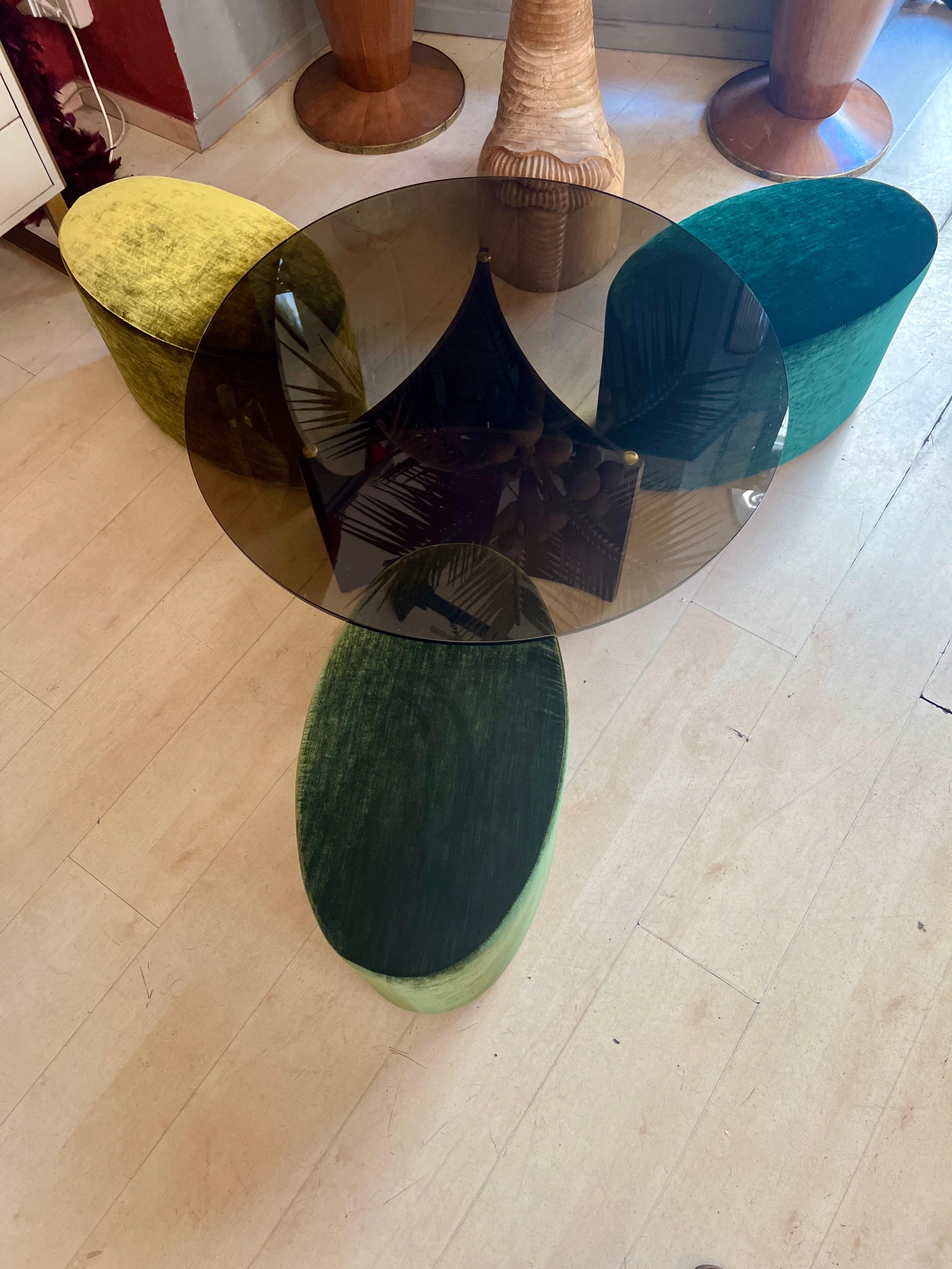 Set of Mid-Century Round Coffee Table and Three Green Velvet Foldaway Poufs.
The top is made of smocked glass, the base is made of palisander wood.
The folaway poufs are newly uphostered in different tones of green changing velvet (acid green, grass