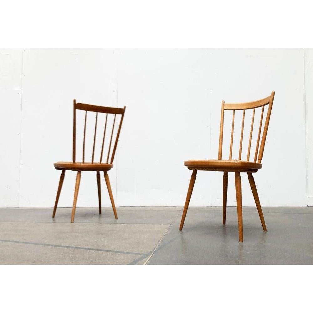 Due sedie Mid-Century a forma di germoglio.

Le sedie ricordano fortemente i design di Arno Lambrecht. Il telaio è composto interamente da elementi in legno massiccio con connessioni talvolta complesse. Lo schienale è leggermente concavo e si