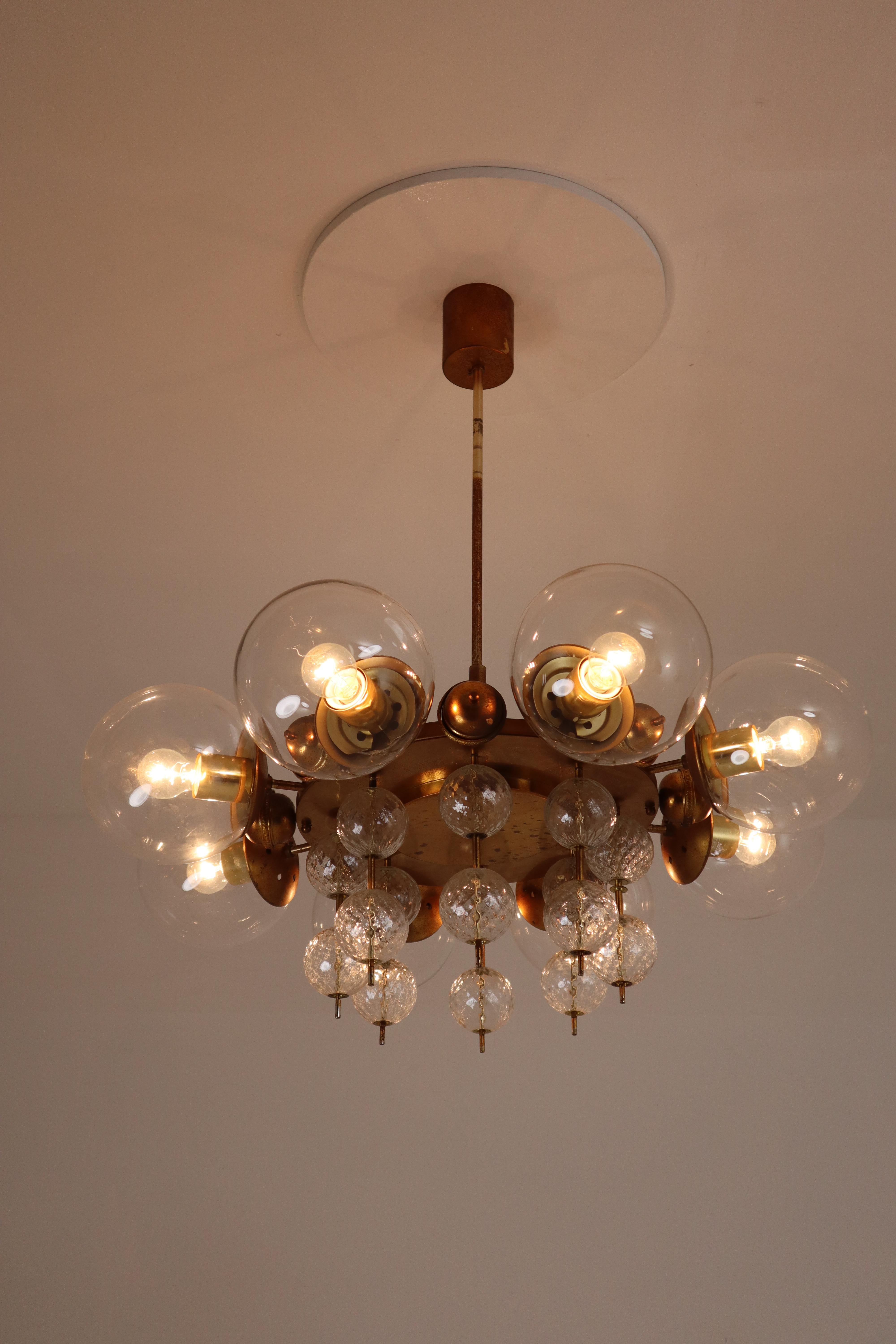 Set of brass chandeliers was produced in Europe in the 1950s. A spirited and chic design set chandeliers with brass fixture and handblown glass. The chandelier with brass frame consist of eight lights, formed in a circle, with glass shades. The