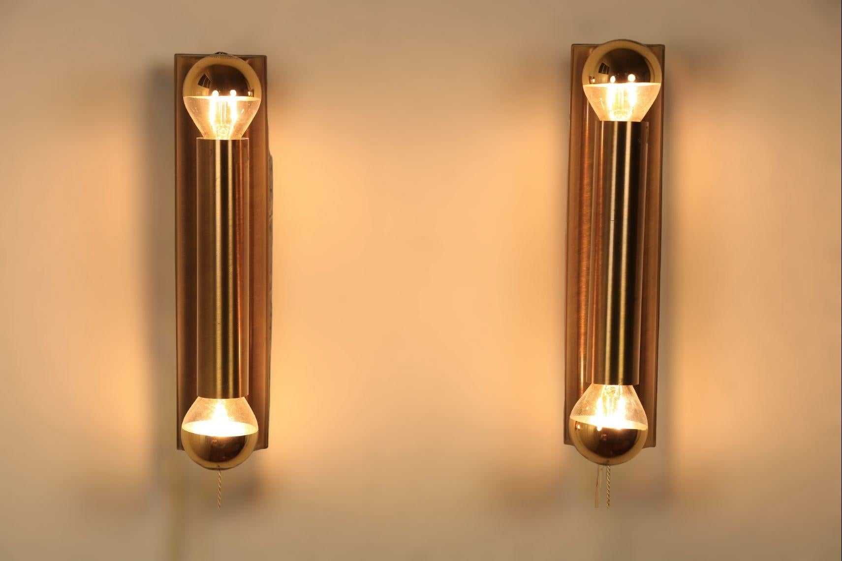 Set of two wall lamps from the late 1970s.

Minimalist design.
Brass. 
Very effective with golden head mirror bulbs (included for Europe).

Measures: Height: 24 cm / 9.45 inch.