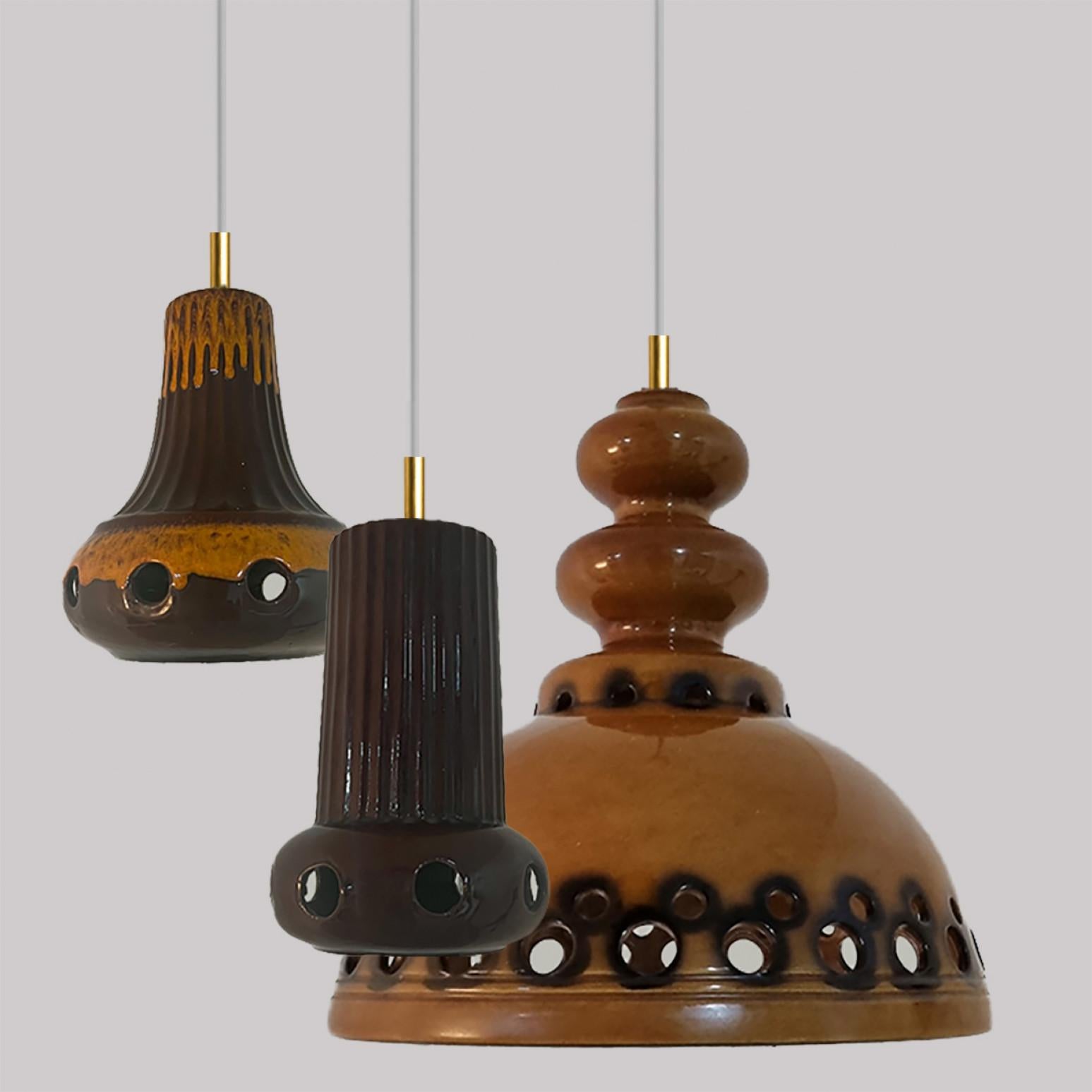 A set of spectacular and stylish ceramic pendant lights made in West-Germany around 1970's. The lights are made of orange and brown glazed ceramic and glazed in 'Fat Lava' style. The orange and brown ceramic fits beautifully with warm, gold or clear