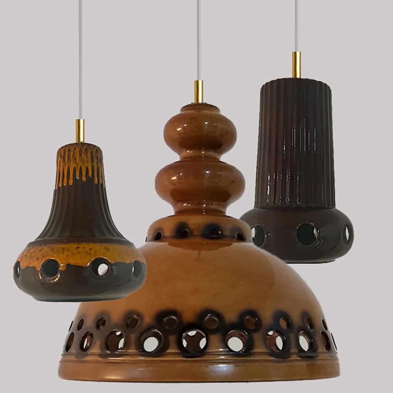 Un set di spettacolari ed eleganti lampade a sospensione in ceramica realizzate nella Germania occidentale intorno agli anni '70. Le luci sono realizzate in ceramica smaltata arancione e marrone e smaltate in stile 