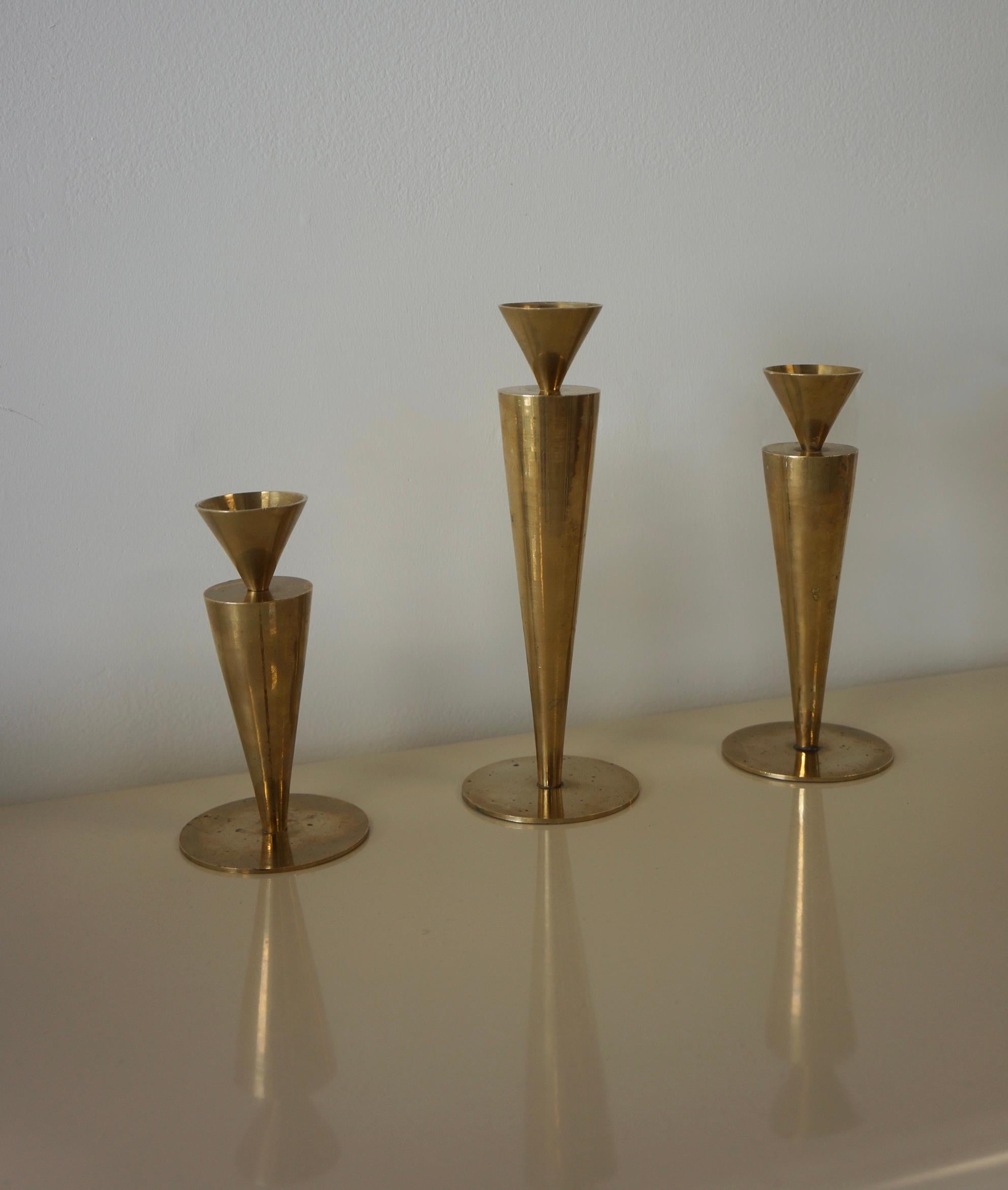 Stunning modernist style brass vintage candle holder as a set of three. Minimalistic yet elegant in design. They are made out of brass. Each piece features a triangular rounded shape mouth with an elongated triangular rounded body which sits on a