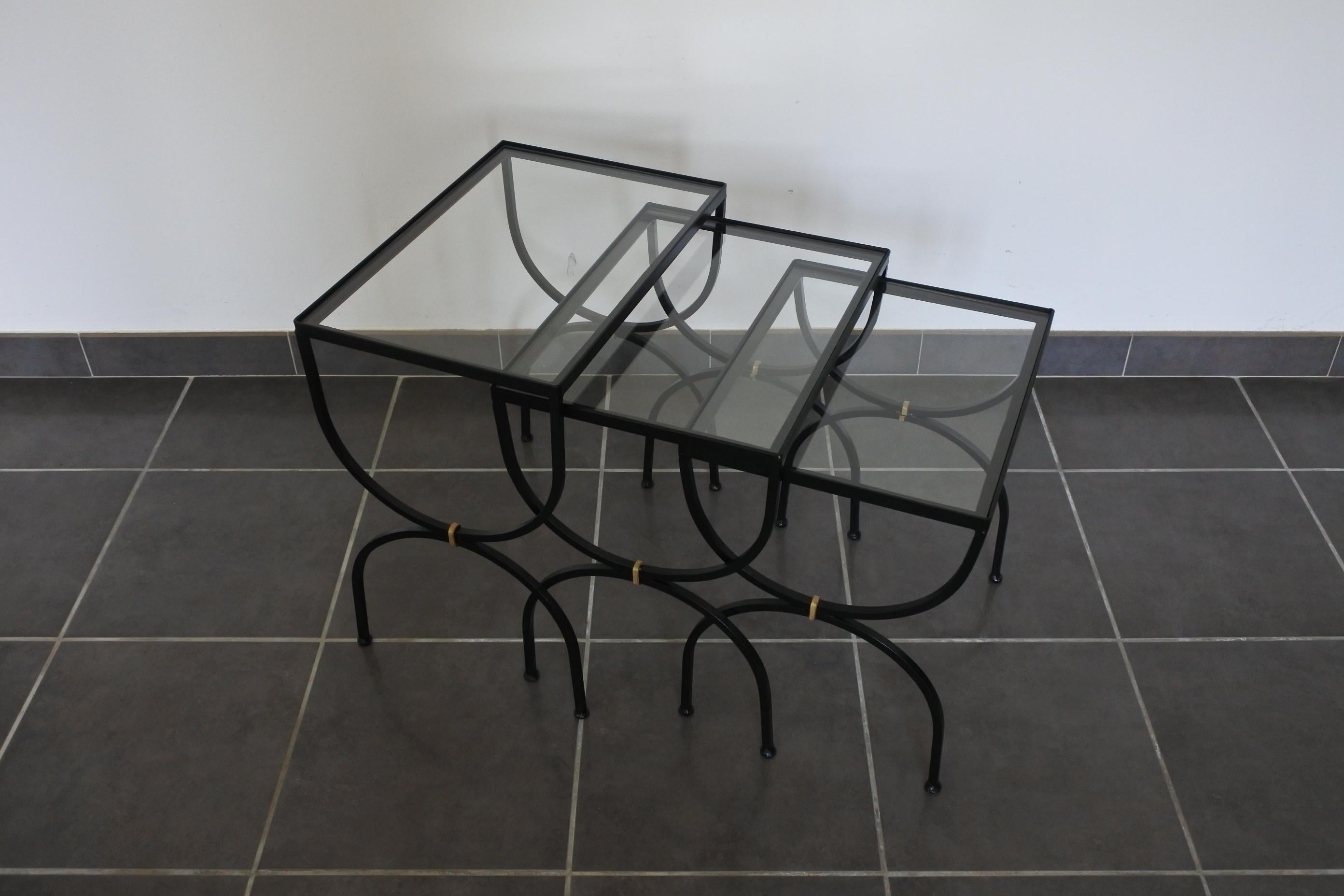 Set of nesting or side tables.
Black lacquered metal with clear glass tops.
Made in France in the 1950s.

Measurements: 
Large D 32 cm, W 46 cm, H 47.5 cm
Medium D 32 cm, W 41 cm, H 44 cm
Small D 32 cm, W 37.5 cm, H 41.5 cm.