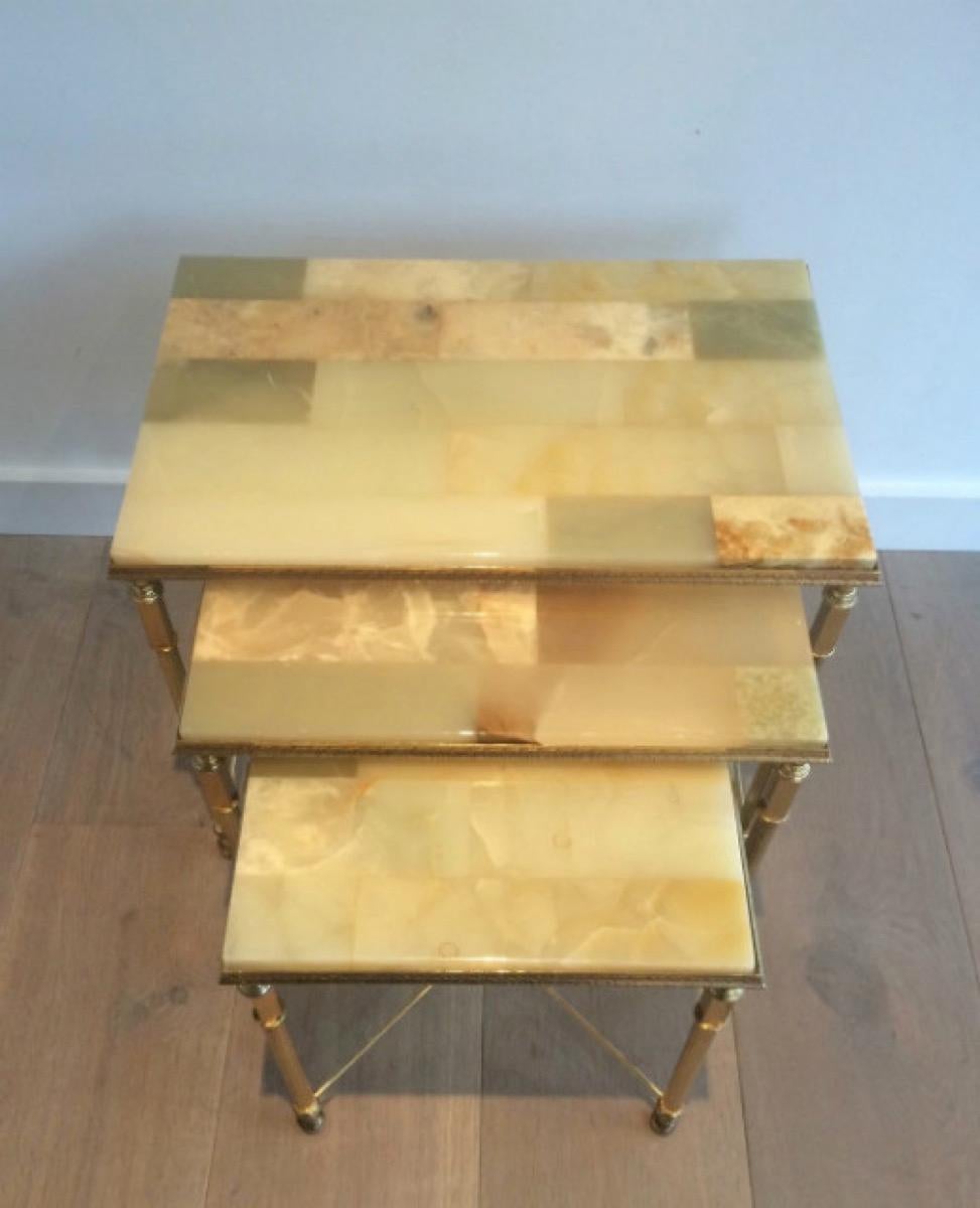 This set of 3 neoclassical nesting tables is made of brass with onyx tops. Each table very nice decorated with a stretcher on the bottom part. The onyx top of the smaller nesting table presents a little lack of material on the top of one corner.