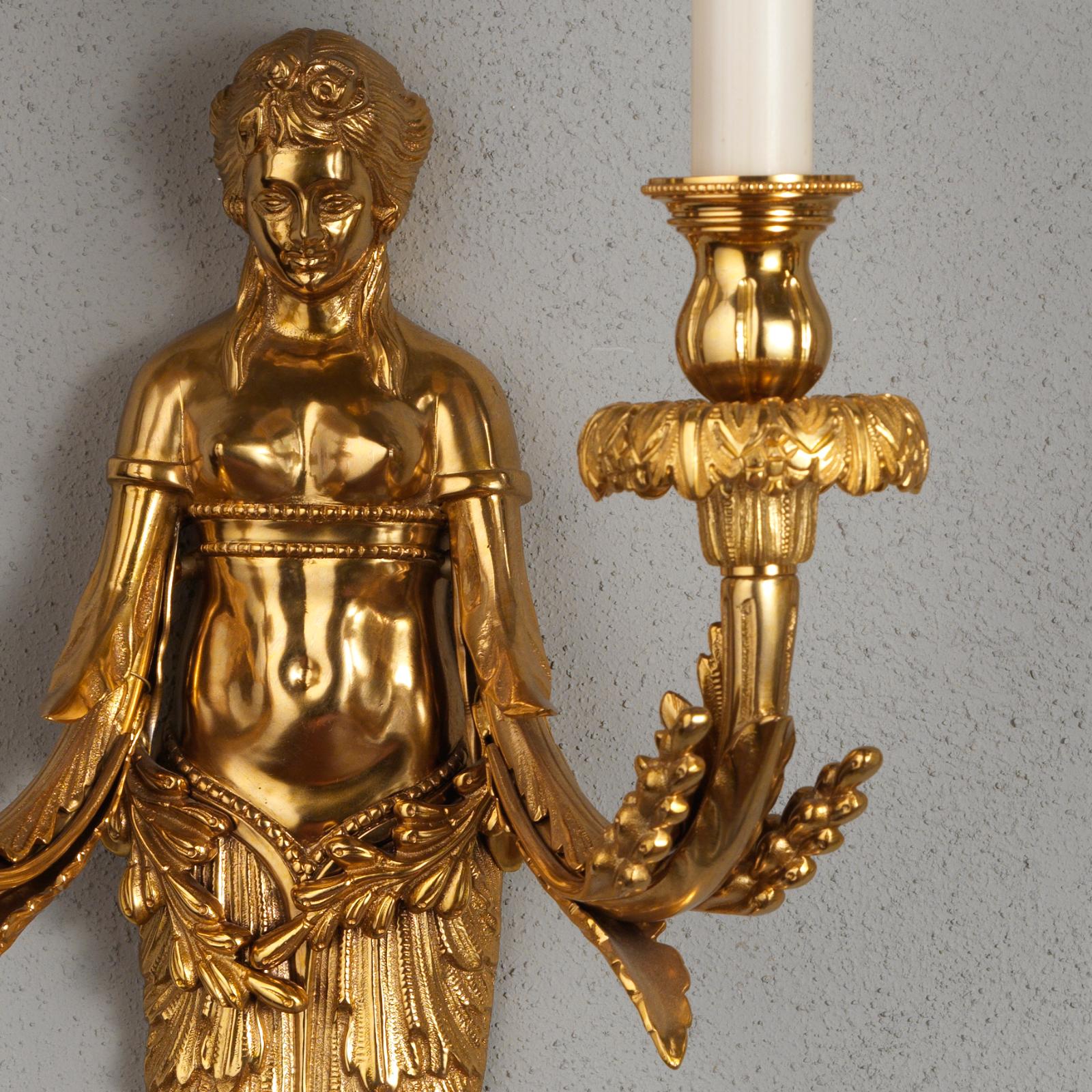 Dekorativer Satz von zwei großen figuralen Wandleuchtern aus vergoldeter Bronze von Gherardo Degli Albizzi. Die weibliche Figur zeichnet sich durch eine sehr reiche pflanzliche Verzierung mit Früchten und Blättern aus, sowohl im unteren Körperteil