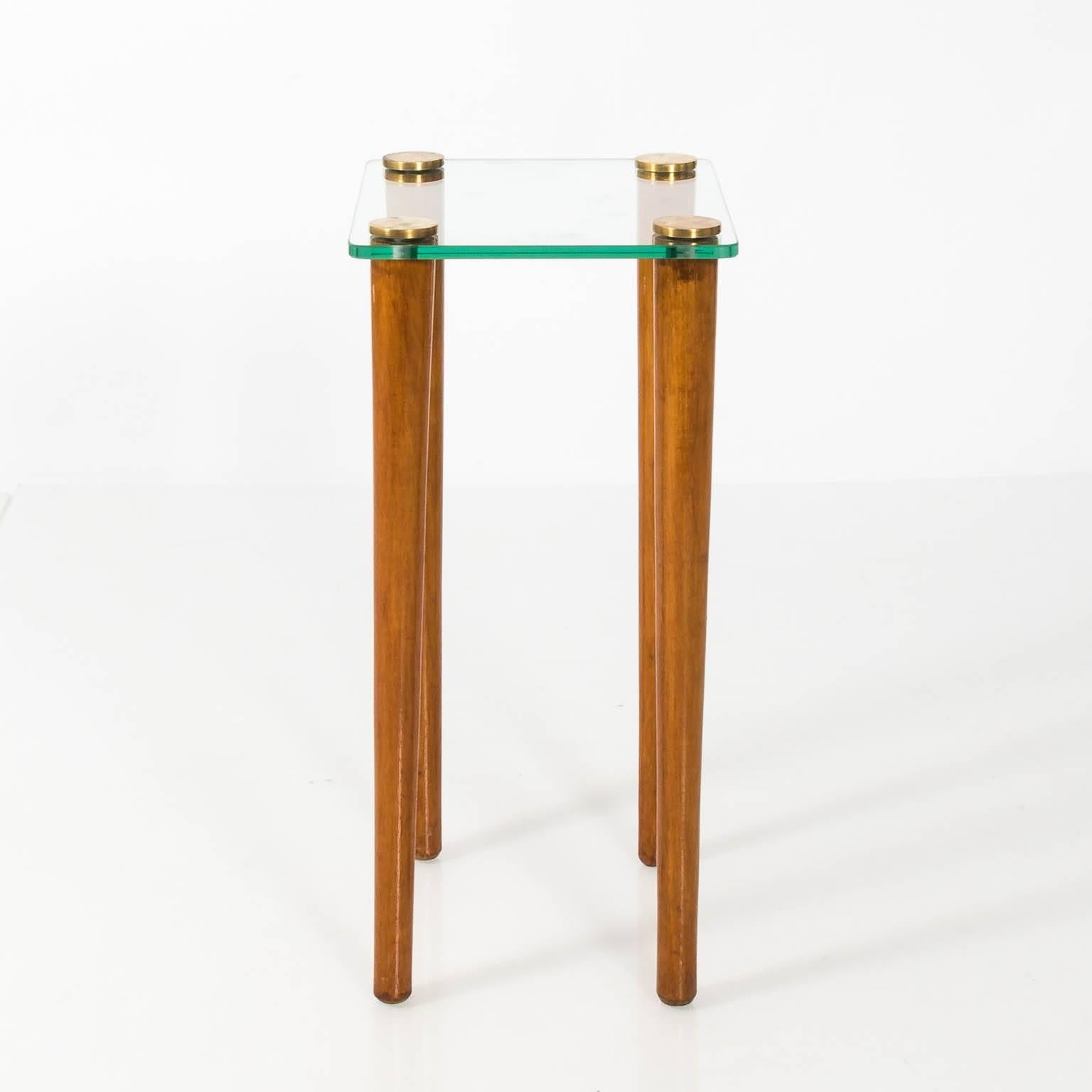 Set of three Mid-Century Modern style glass and wood nesting tables by Gilbert Rohde, circa 1950. The largest table measures: 14.00 inches wide by 24.00 inches height by 24.00 inches depth; the middle table measures 19.00 inches wide by 23.00 inches