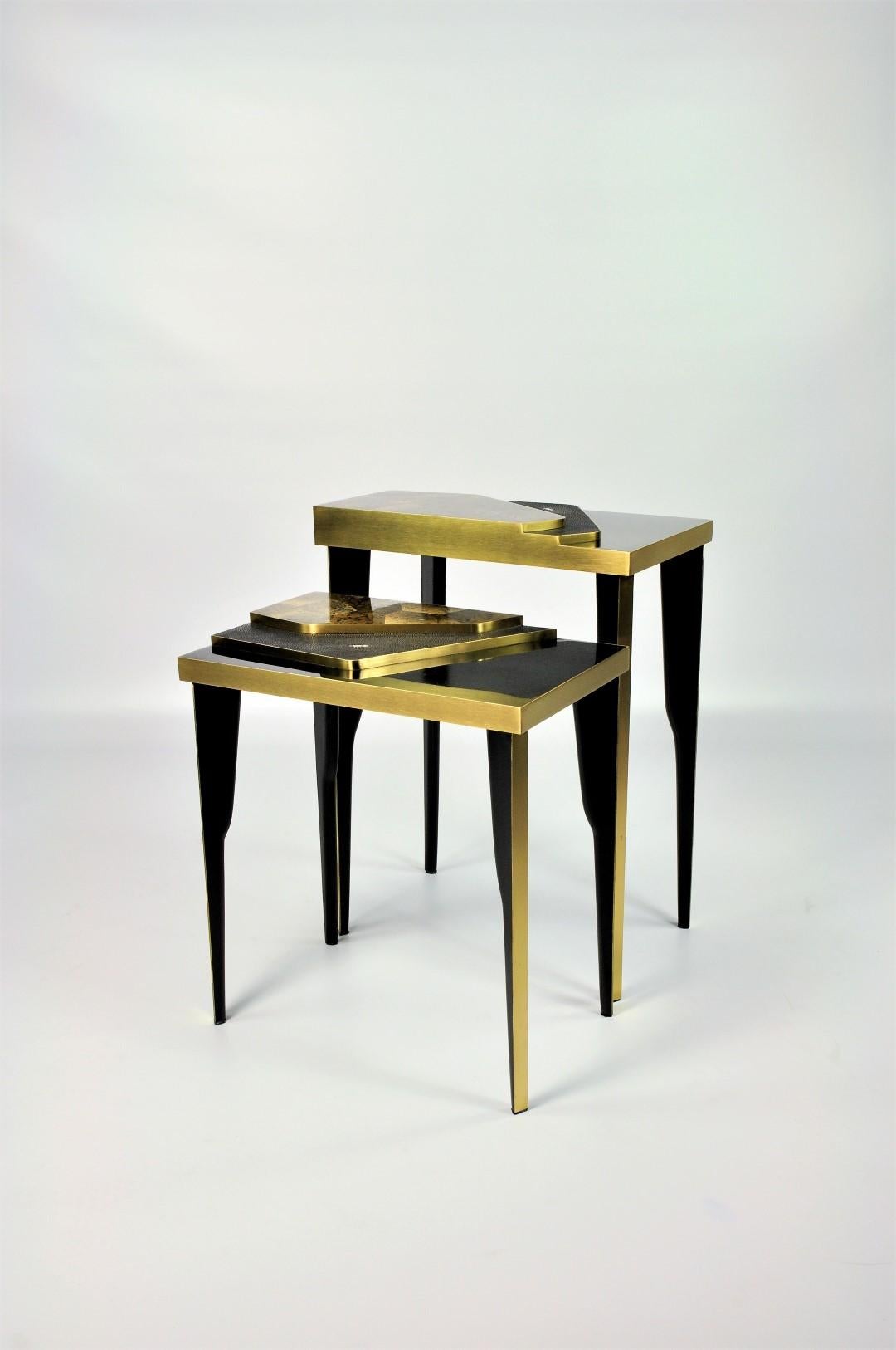 The set of 2 nesting tables is made of a polished black shell marquetry top with 2 levels made of shagreen and stone marquetry.
All the edges have brushed brass trims and the feet are in black wood.

A very exclusive set of nesting tables for