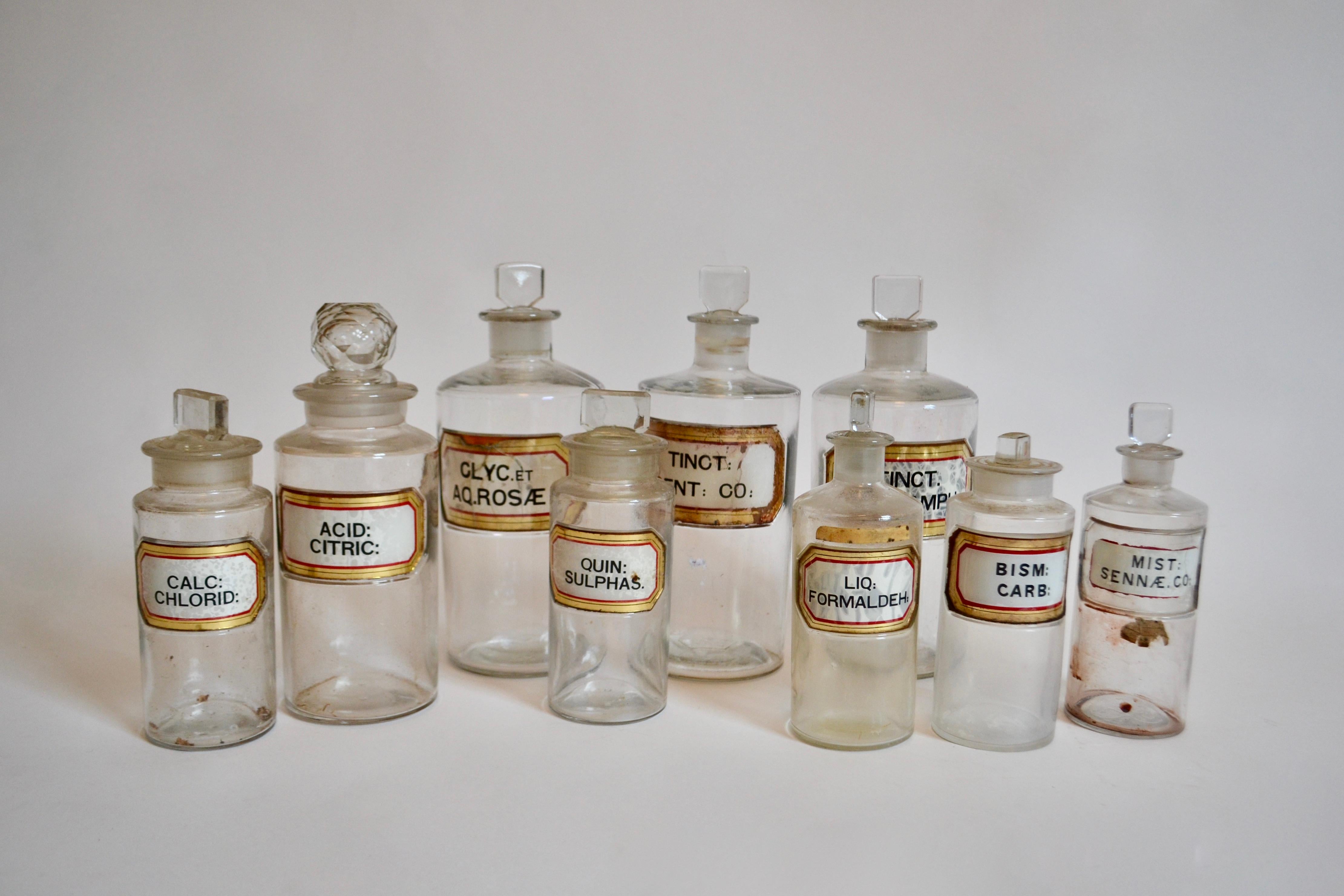 A set of nine 19th Century Victorian antique glass apothecary / chemist / medicine bottles of cylindrical form with original glass stoppers to the top, each having original applied labels with abbreviated Latin names to include; Liq Formaldeh, Pulv