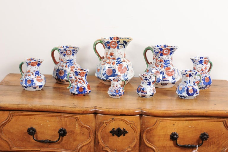 A set of nine Mason's ironstone hydra pitchers from the mid-19th century, with blue, orange and green Japan Basket pattern. Created in England during the 1850s, each of this set of nine pitchers captures our attention with its octogonal shape