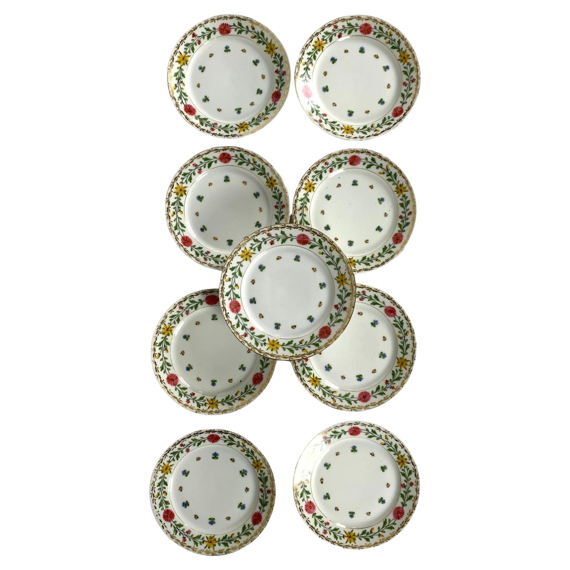 This set of nine lovely Vieux Paris dishes was made by Haviland Limoges in France circa 1876.
The border of the dishes features pink and yellow flowers on a vine with green leaves.
Additionally, there is a gilded wreath of leaves along the