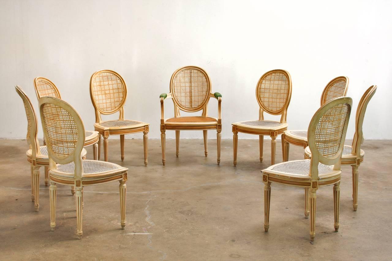 Elegant set of nine lacquered and caned dining chairs made in the French Louis XVI style. Set consists of eight dining side chairs and one armchair (Measures 23.5