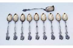 Set of nine silver coffee spoons and sugar scoop with scalloped handles