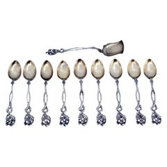 Set of nine silver coffee spoons and sugar scoop with scalloped handles