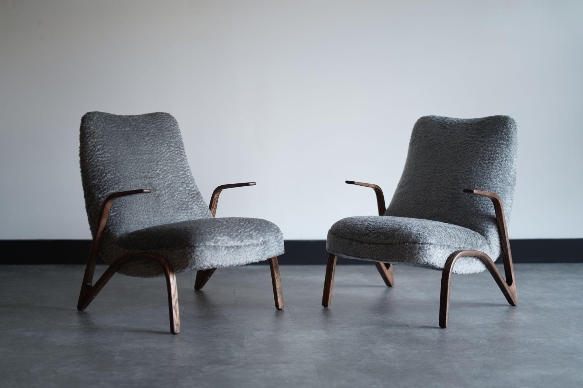 Elevate your interior with this striking set of lounge chairs by Paul Bode for Federholz Gesellschaft OHG, circa 1960s. Originally crafted in Germany, these chairs feature fully restored sculptural oak frames and are luxuriously reupholstered in