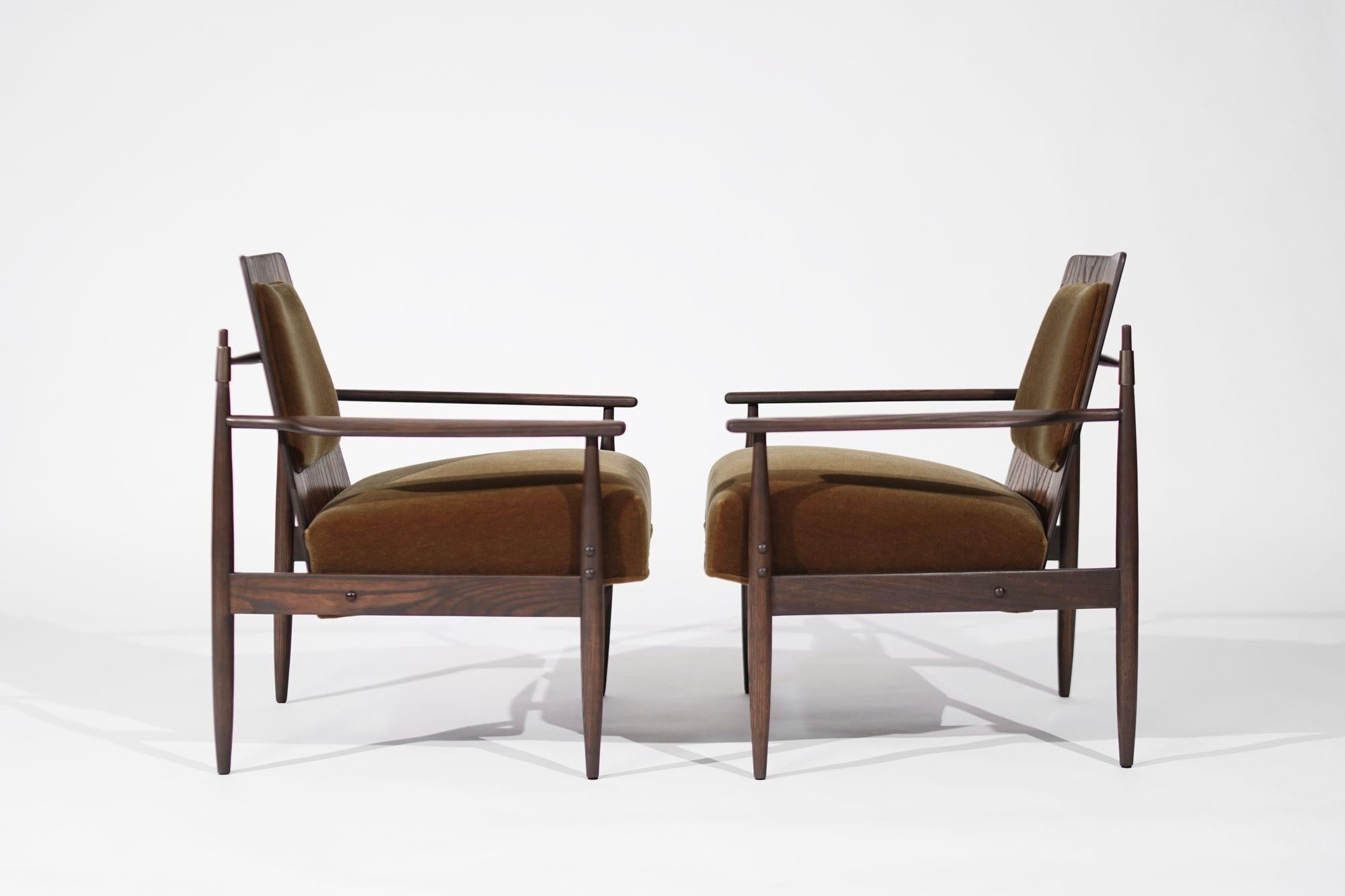 Immerse yourself in mid-century modern elegance with this exquisite pair of lounge chairs by renowned designer Dan Johnson, crafted circa 1950-1959. These chairs boast a sturdy oak framework, luxuriously soft mohair upholstery, and exquisite bronze