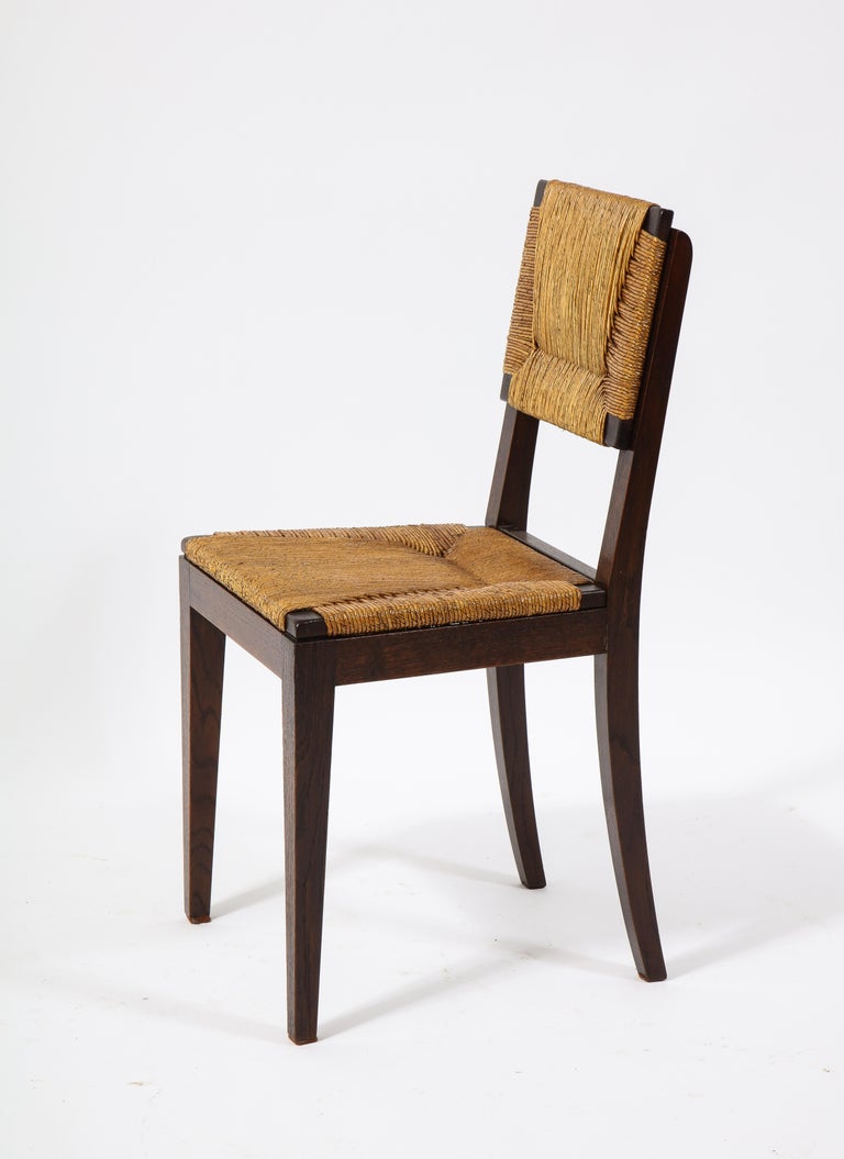A set of rushed oak chairs with a very modern design. The backs have a very distinctive construction. The geometric weaving of the rush sets the chairs apart from similar models of the era.