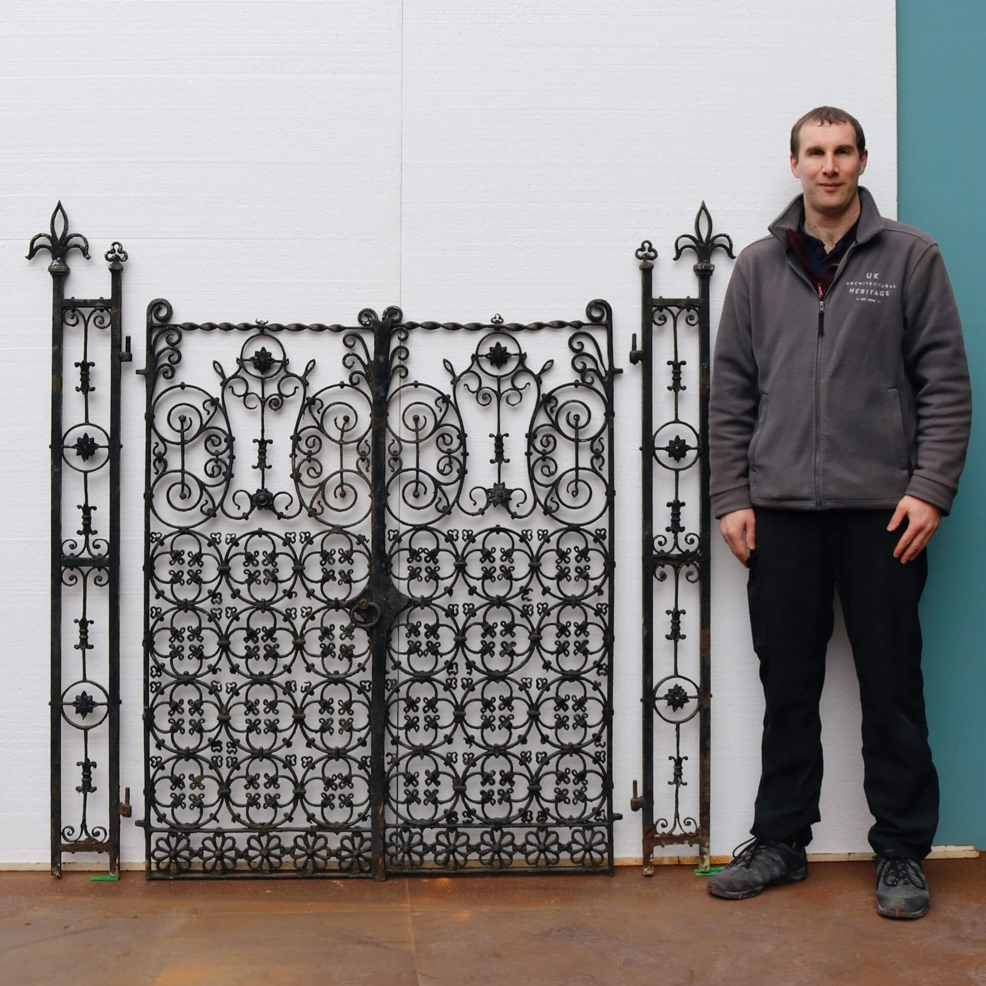 A highly ornate set of late Georgian wrought iron garden gates with accompanying posts handcrafted at the hand of a talented 19th century blacksmith. These beautiful English gates are in original condition and while there are a few historic repairs