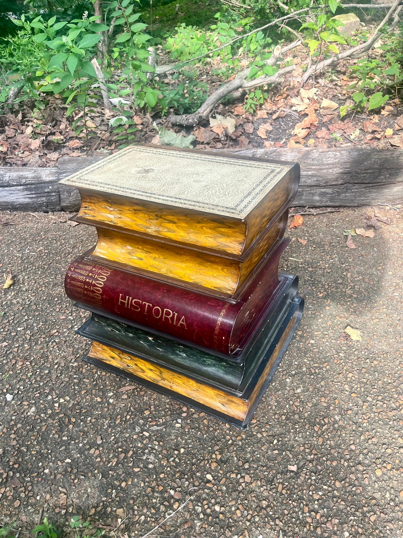 This is an interesting and well painted tole metal end or side table styled after a stack of books or ledgers in liberal arts . The pages are faux painted to simulate the pretty marbleized pages of old books .The table is in  good antique condition