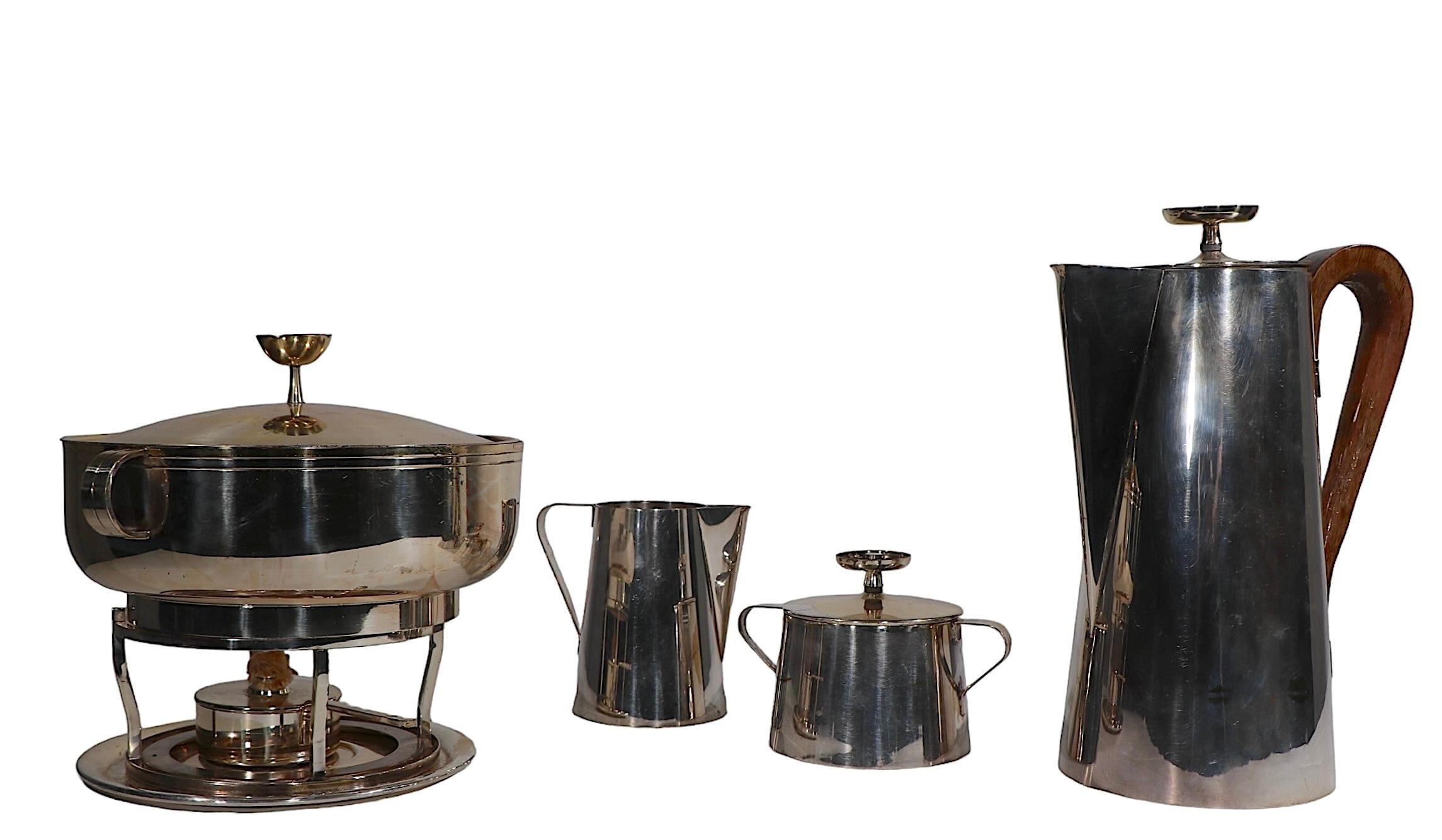 Group of silver plate serving pieces designed by Tommi Parzinger for Meuck - Cary circa 1950/60's. This lot includes a coffee pot, sugar bowl, creamer, and a fondue dish. All pieces show some wear, specific condition report as follows. 
 Coffee Pot
