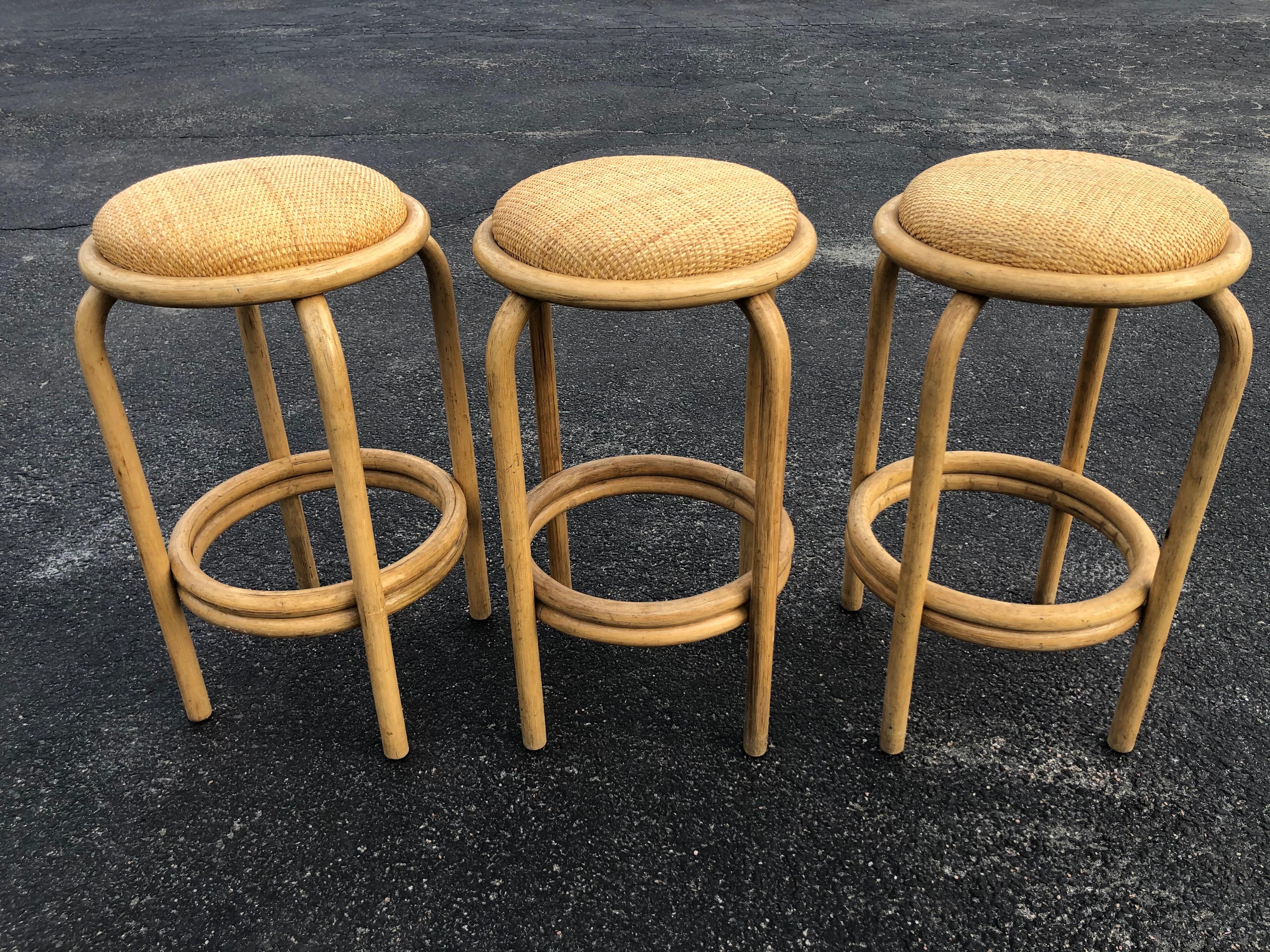 Set of Paul Frankl style rattan bar or counter stools. Classic timeless stools with a natural wicker rounded seat cushion. The set includes three stools.