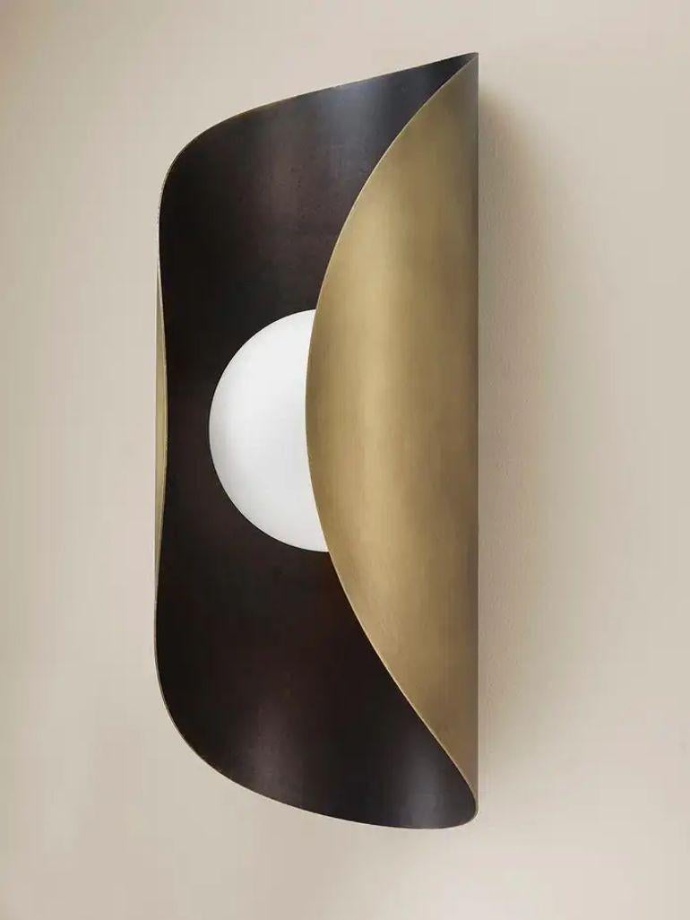 Drawing inspiration from nature's exquisite treasures, Perla evokes the image of a pearl emerging from within a shell, with a delicately curved metal shade enveloping a blown glass bulb like a luminous gift. Versatile and elegant, the Perla wall