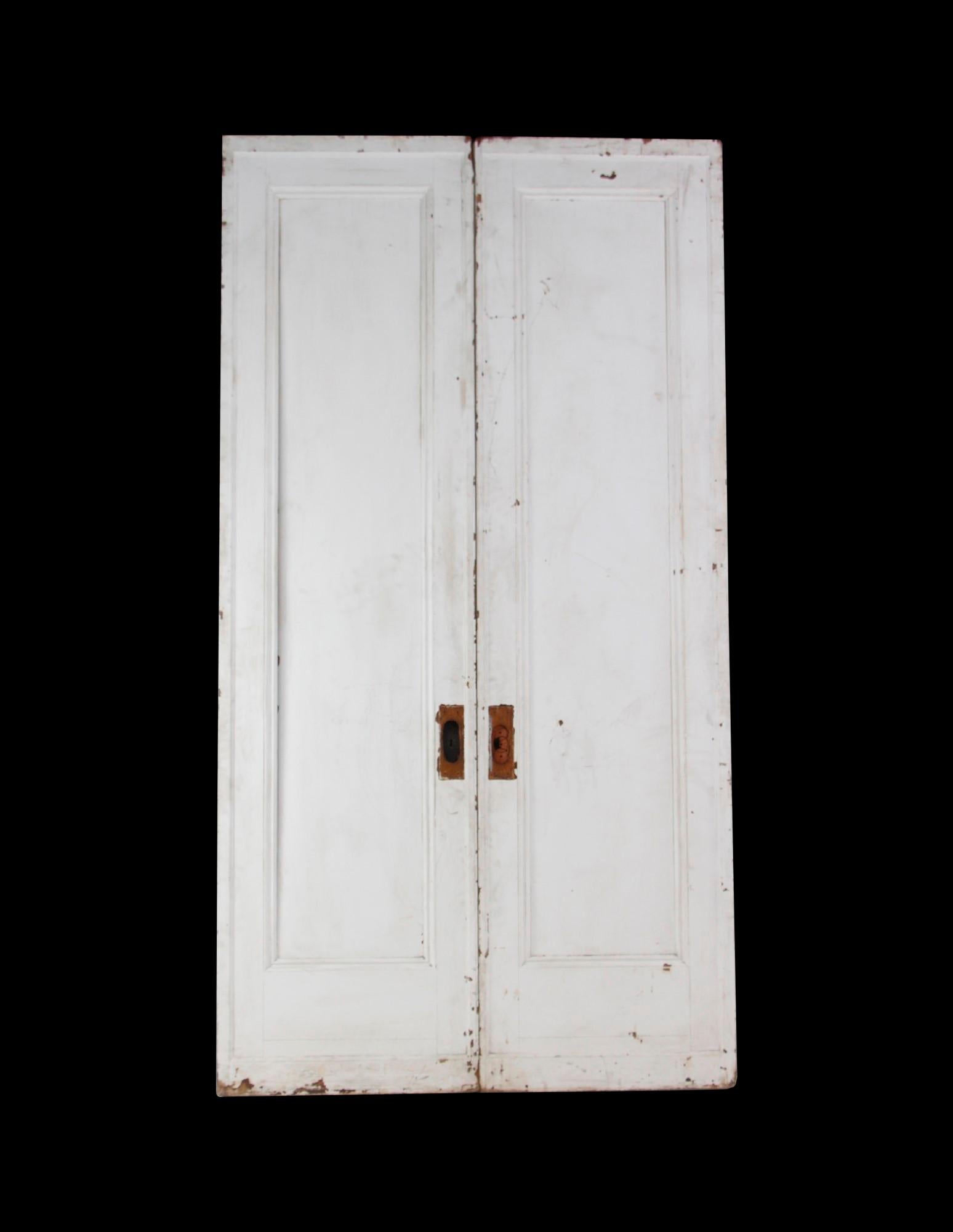 Antique dark tone wood double pocket doors painted white on one side. They are tall and slender featuring a single vertical panel. Priced as a double. This can be seen at our 400 Gilligan St location in Scranton, PA. Measures: 105.78 x 56.25.