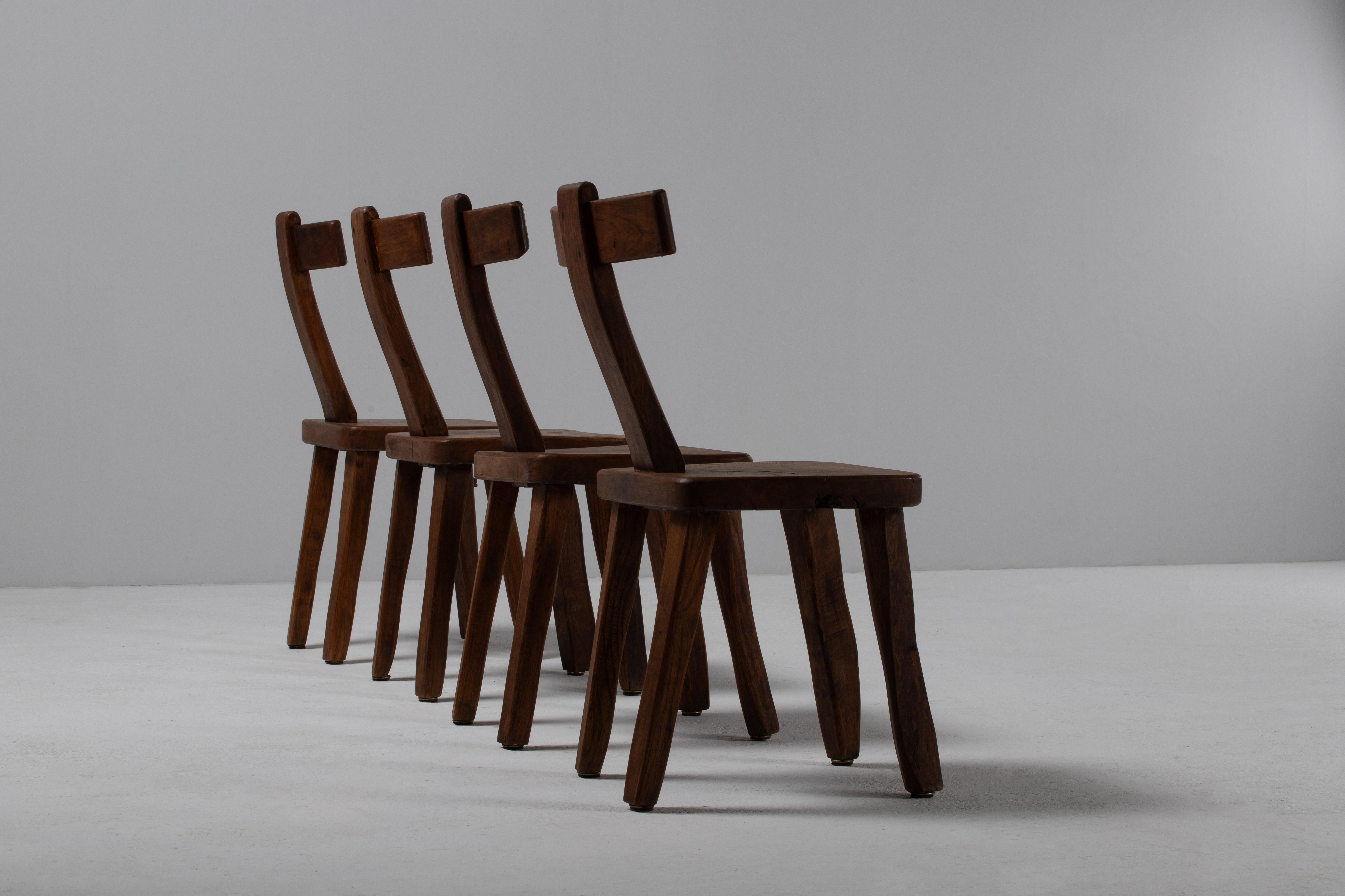Questo straordinario set di sedie brutaliste dell'inizio del XX secolo è attribuito al designer finlandese Olavi Hanninen, noto per il suo approccio grezzo e scultoreo all'arredamento. Realizzate in legno massiccio, queste sedie presentano