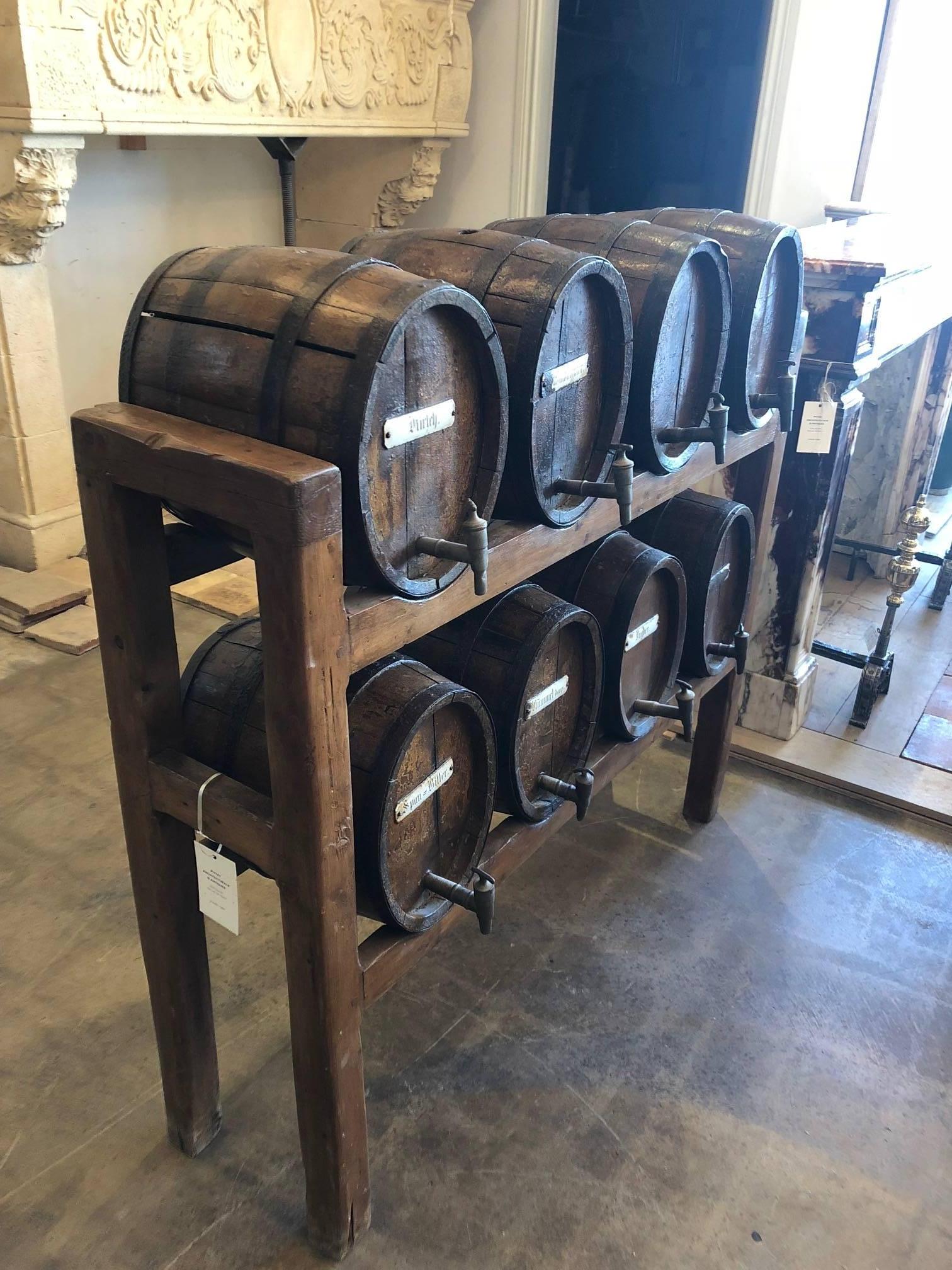 This is a rare set of old oak bourbon whiskey casks. Eight antique, metal banded, whiskey barrels displayed on a custom wooden rack, the barrels are a bit warped and they have a few chips off the top which really highlights the age and character of