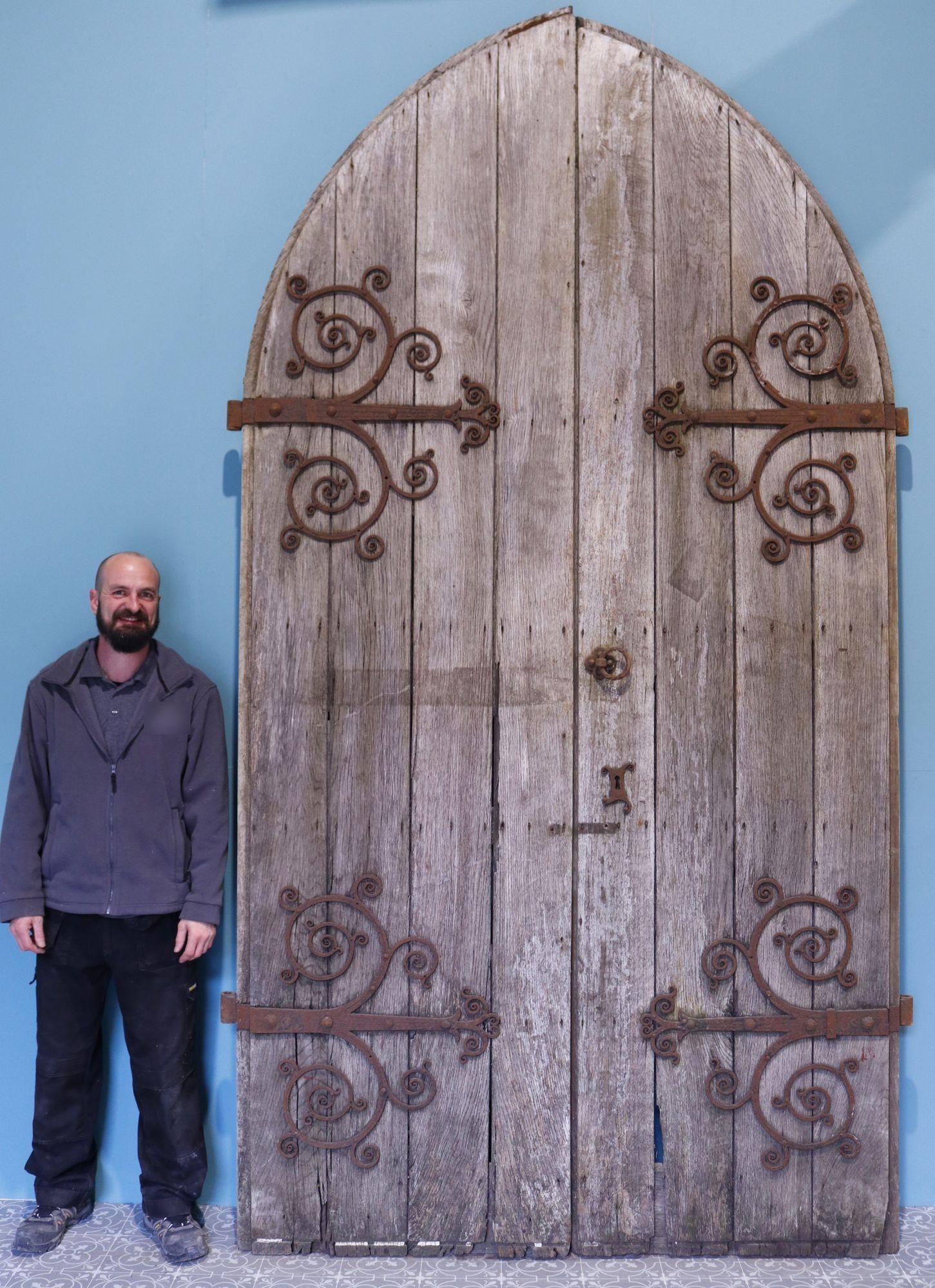 Set of reclaimed Gothic Church doors. A set of large arched antique doors with original hardware and a weathered time worn appearance. These wonderful oak doors feature fantastic blacksmith made wrought iron hinges and door bolts.