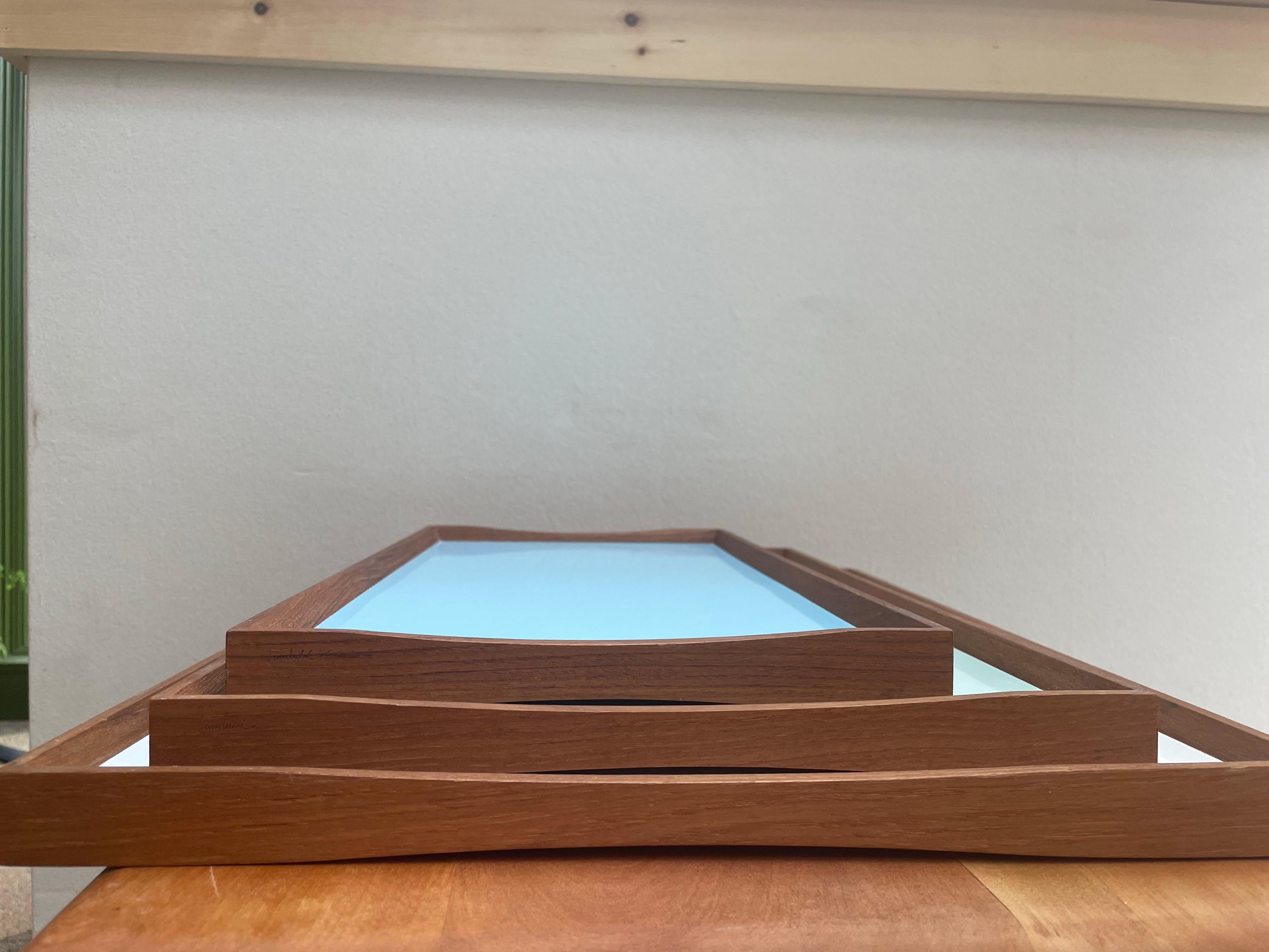 This iconic set of three Turning Trays was designed by Finn Juhl in 1956 and produced by ArchitectMade, Denmark. Each tray is crafted with a gently curved solid teak frame and a reversible laminate surface, showcasing a different color on each