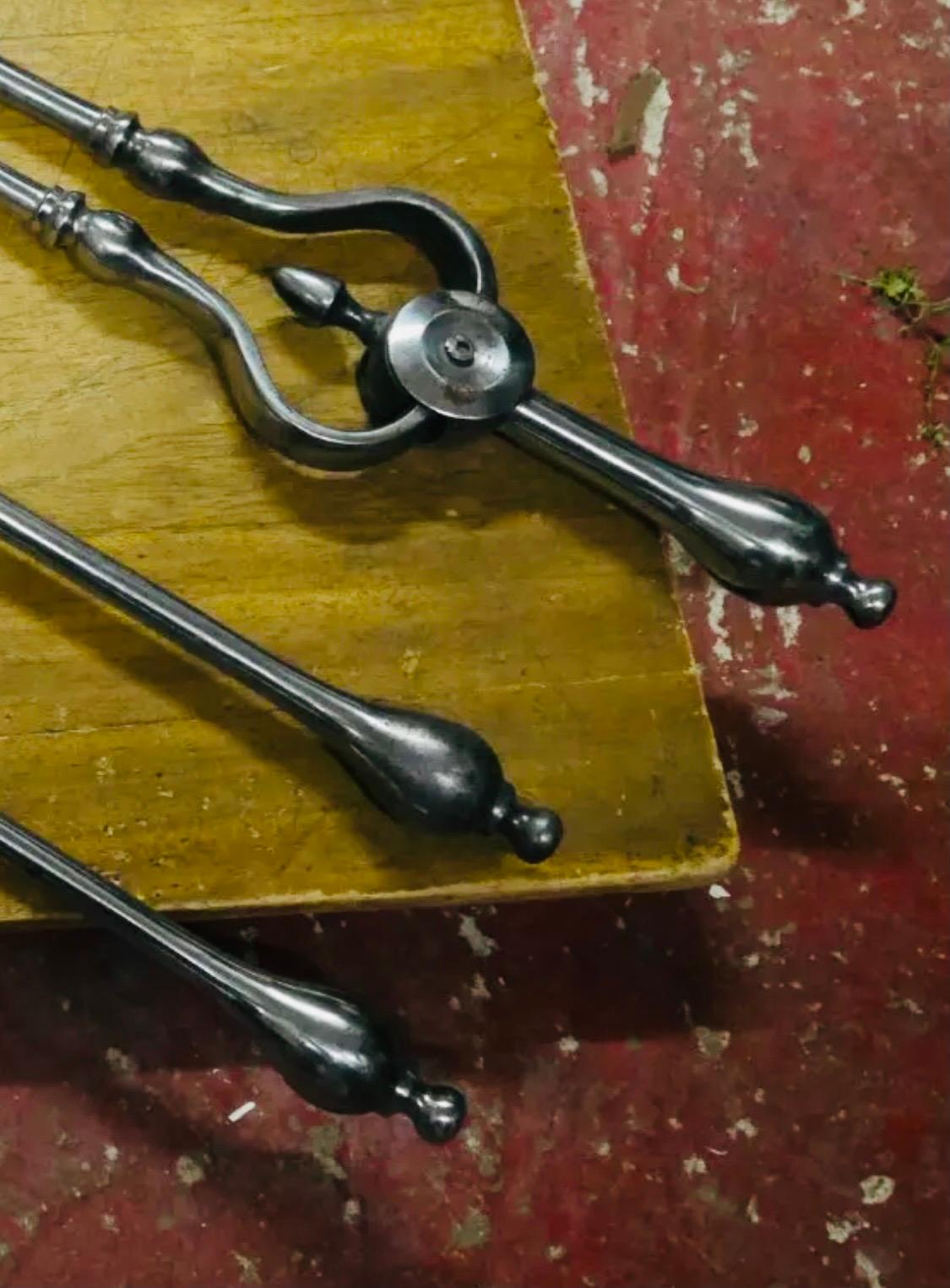 Charmant ensemble de fers à repasser en acier géorgien du début du 19e siècle comprenant un tisonnier, une pince et une pelle avec une lame décorative percée, tous avec des embouts allongés en forme de boule.

Écossais, vers 1820.