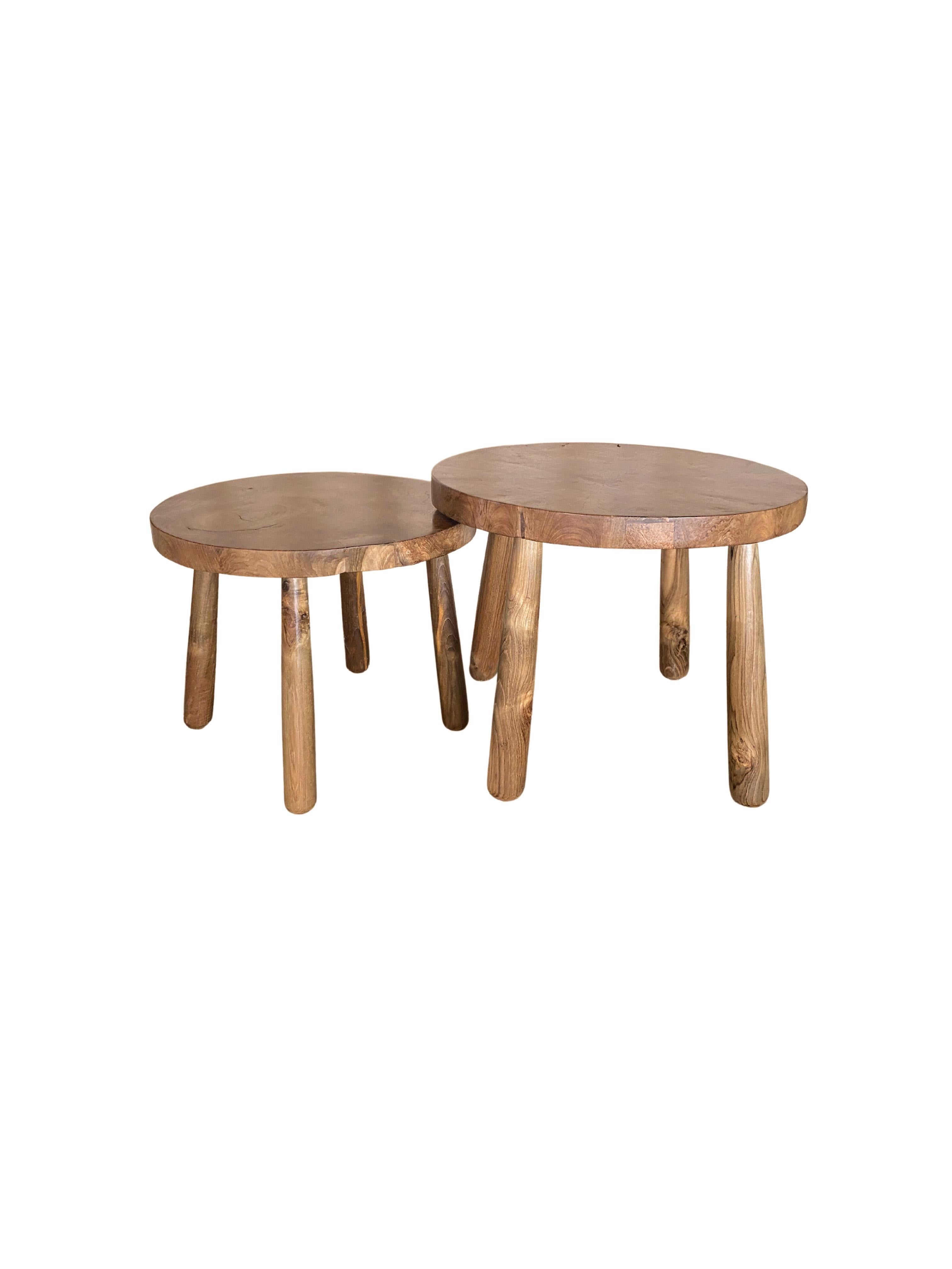 A set of sculptural teak wood side tables which feature an incredible teak burl wood patterning on their table tops. Carved from a single block of wood to find teak patterning as intricate as these is hard to come by. The tables feature four curved