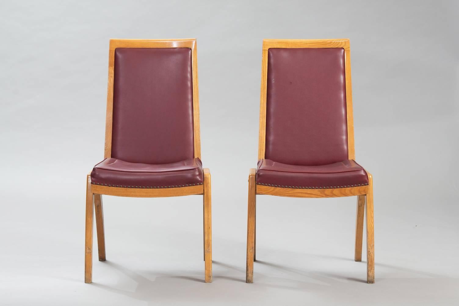 Set of seven ash dining chairs upholstered in a Bordeaux faux leather.