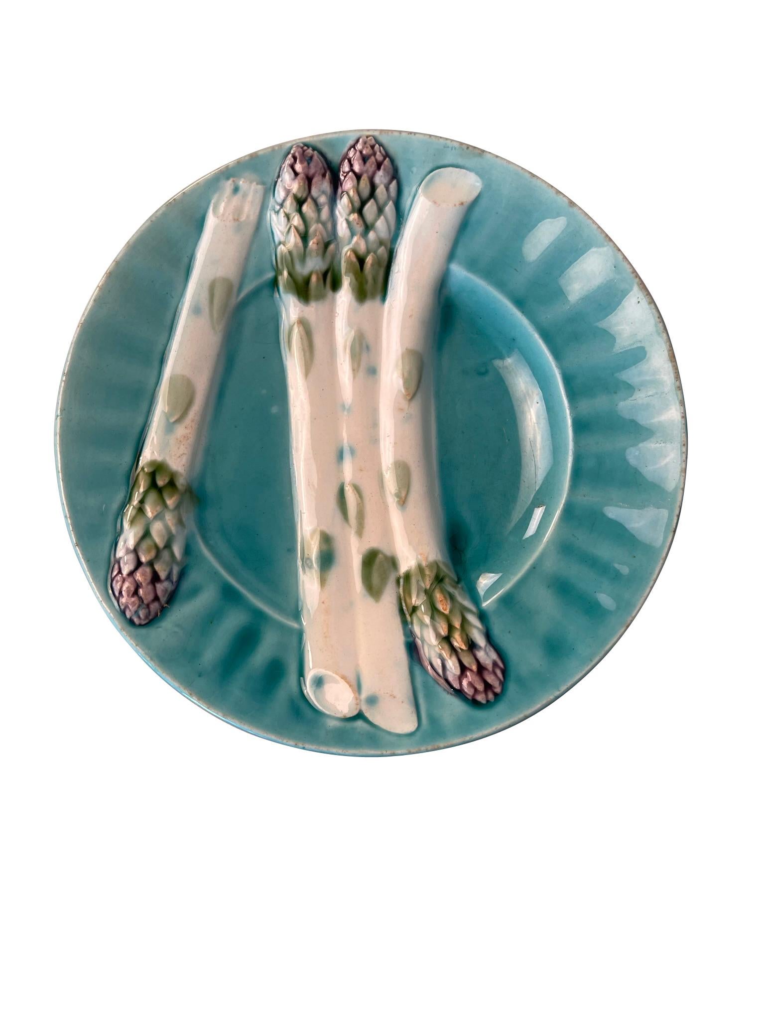 Lot of 7 French Majolica Depose KG Luneville asparagus plates from the Keller and Guerin Frers era. They are decorated in turquoise blue with white and green asparagus images. Decorative enough to hang on a wall or lovely in a dresser.

Lunéville
