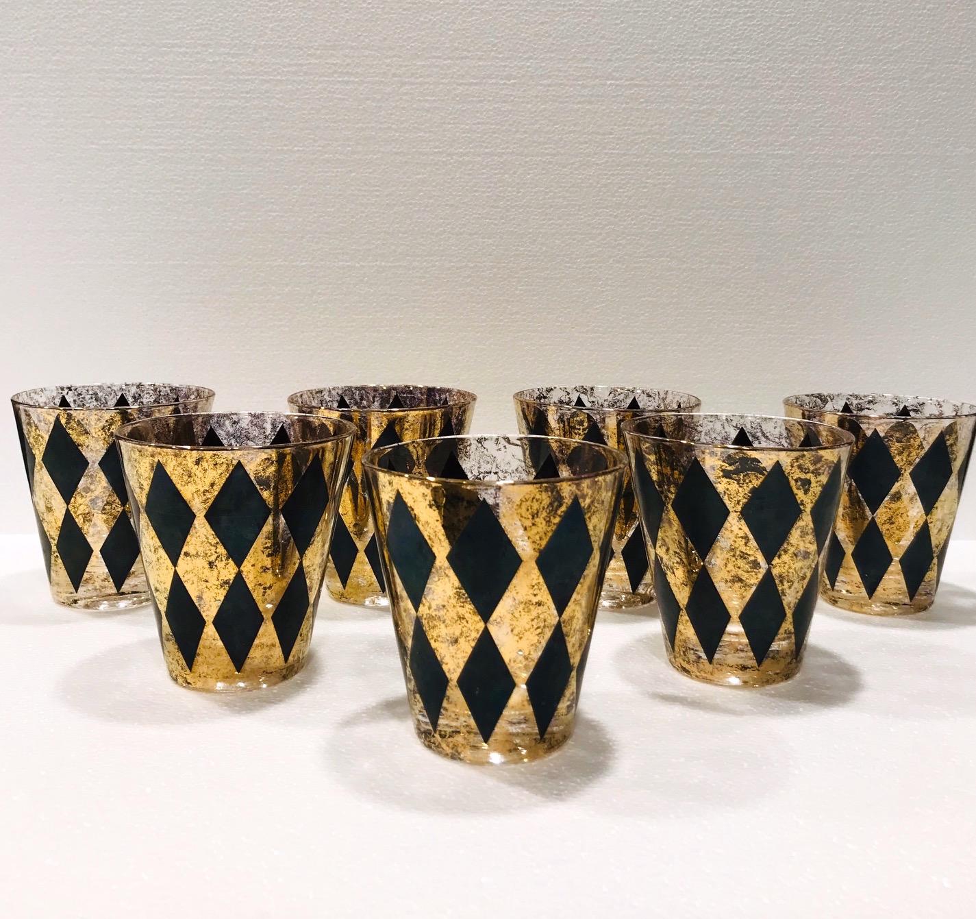 Set of seven Mid-Century Modern rock glasses with Harlequin design. Whiskey cocktail set features large hand blown glass with tapered design with 22-karat gold leaf flecks and black diamond patterns throughout. Hollywood Regency set makes a chic