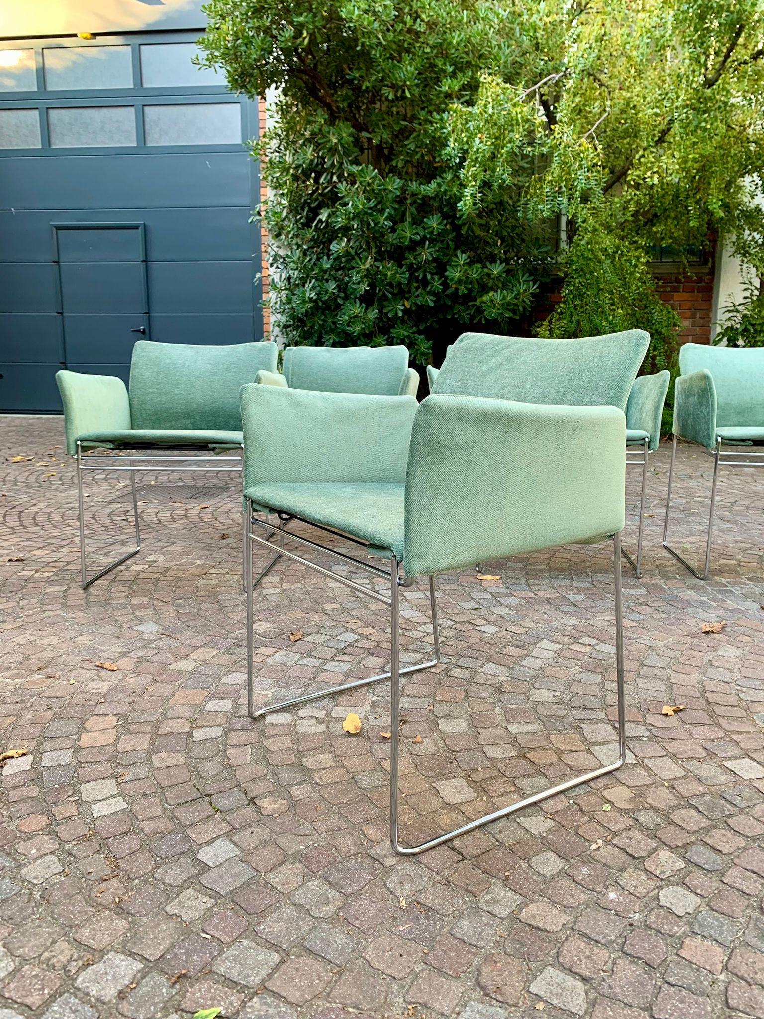 Ensemble de sept chaises Maja avec assise rembourrée et recouverte de tissu. Le cadre tubulaire en acier inoxydable est visible. Le tissu de l'assise est soutenu par le bas par des sangles élastiques noires.

Produit par Cassina dans les années