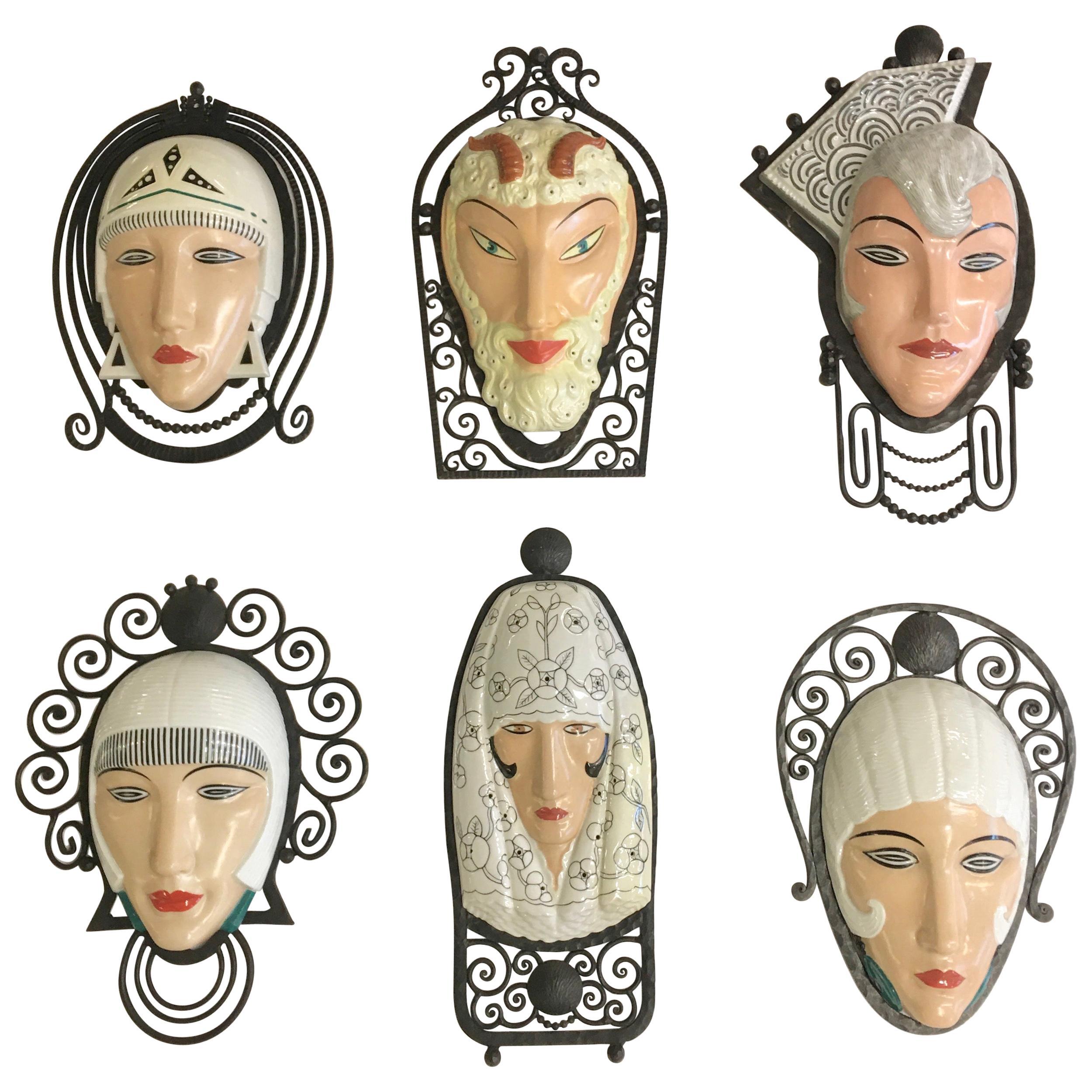 Exceedingly rare collection of seven (7) unique wall mounted porcelain masks mounted in fer forge frames, all signed M. Bever Paris, Made in France, circa 1925. 
The iron frames are stamped 'France' and were made to be electrified and illuminated