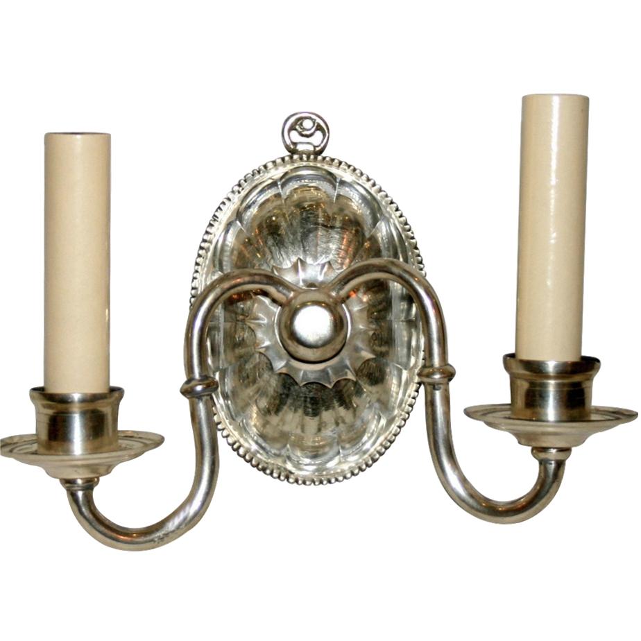 Set of eight circa 1940s English silver plated double light sconces with original finish and molded glass backplate. Sold per pair.

Measurements:
Width 10